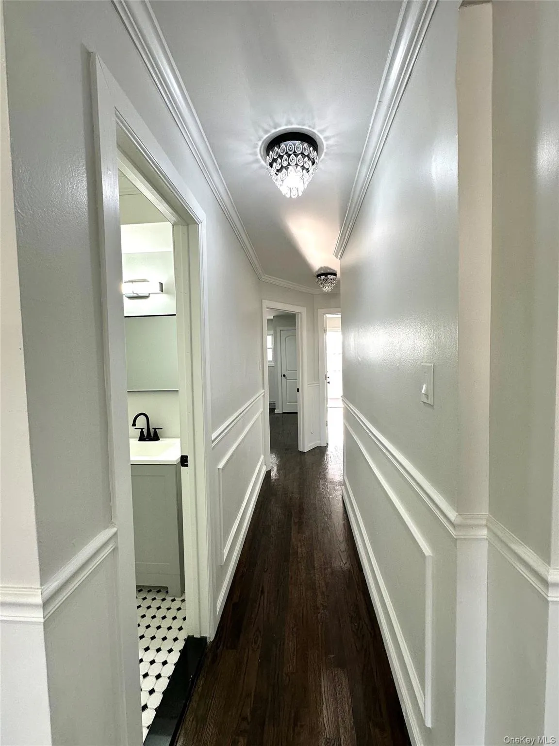 Corridor featuring ornamental molding, dark wood finished floors, and a decorative wall Corridor featuring ornamental molding, dark wood finished floors, and a decorative wall