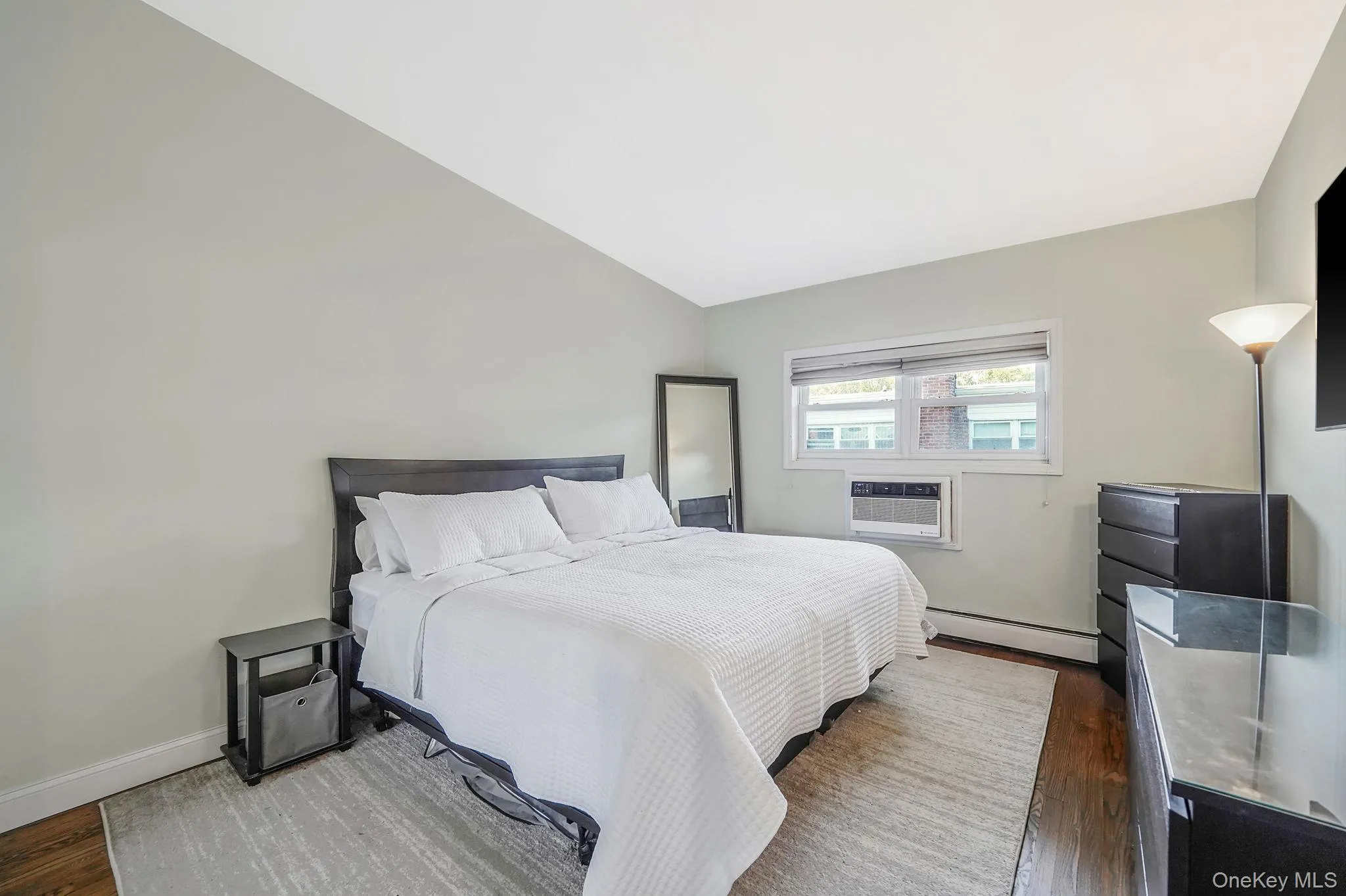 Bedroom featuring baseboard heating, vaulted ceiling, and wood finished floors Bedroom featuring baseboard heating, vaulted ceiling, and wood finished floors