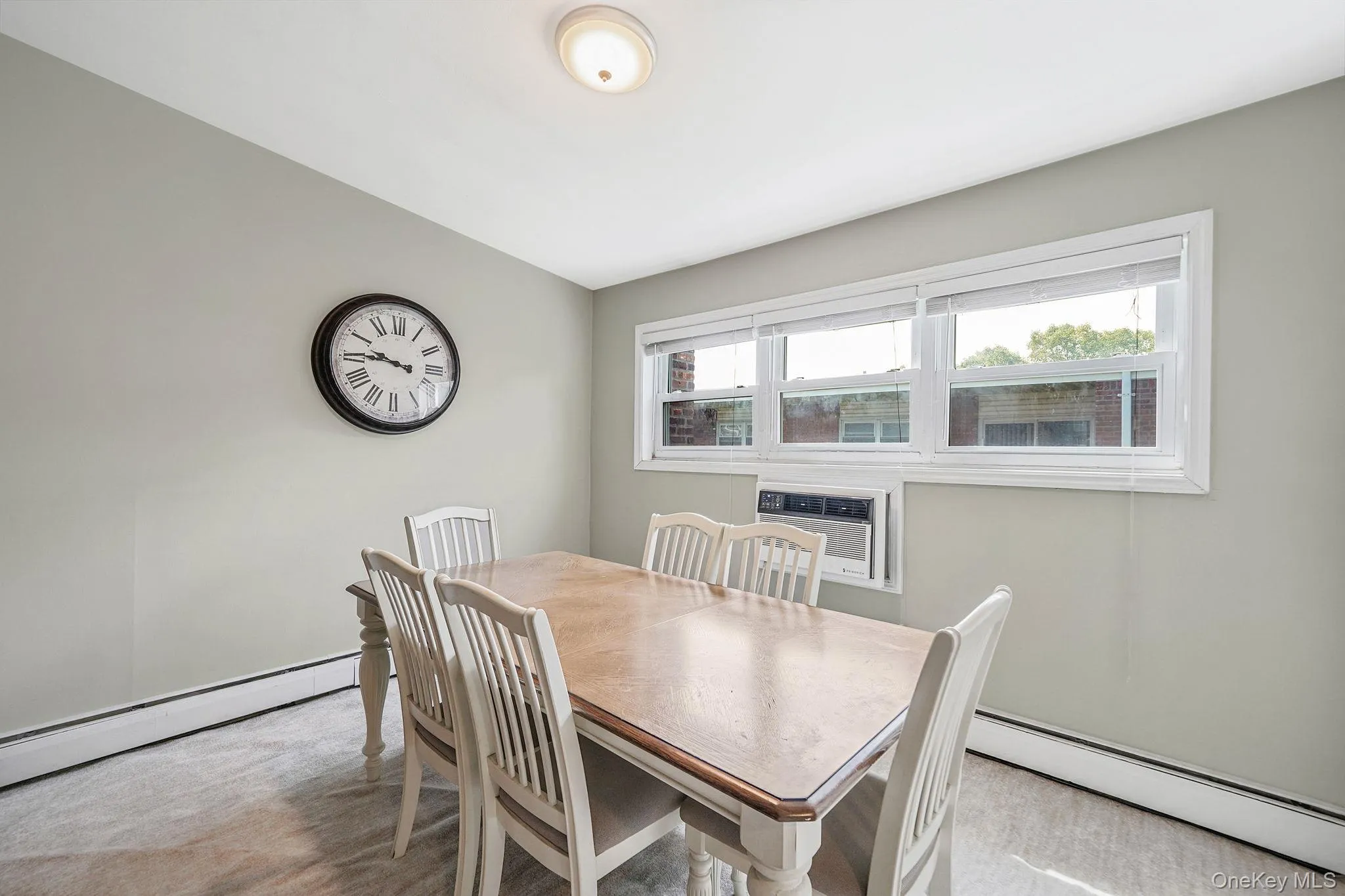 Dining room with baseboard heating, light carpet, and a wall mounted AC Dining room with baseboard heating, light carpet, and a wall mounted AC
