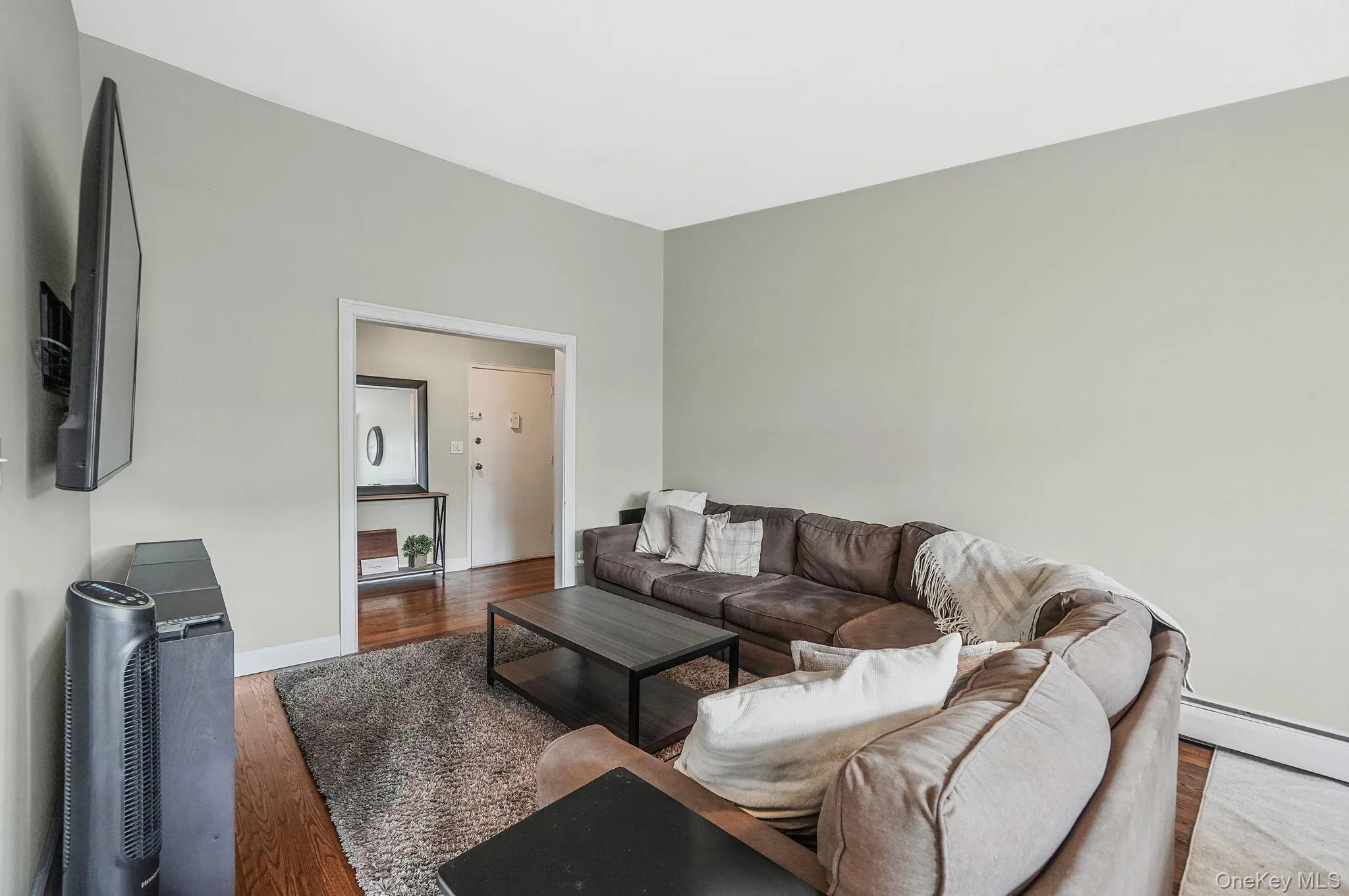 Living area featuring wood finished floors and a baseboard heating unit Living area featuring wood finished floors and a baseboard heating unit