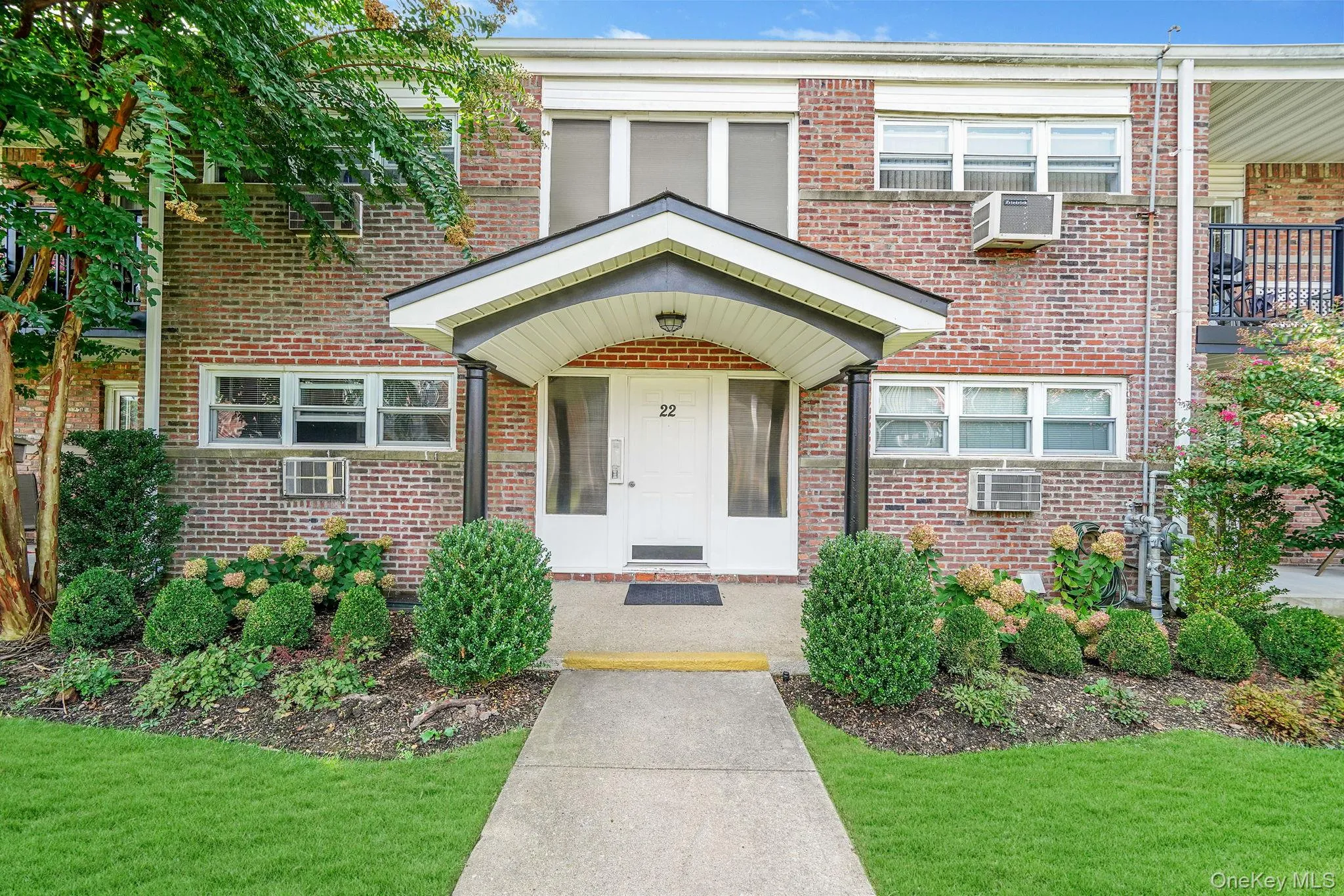 Doorway to property featuring brick siding and a lawn Doorway to property featuring brick siding and a lawn