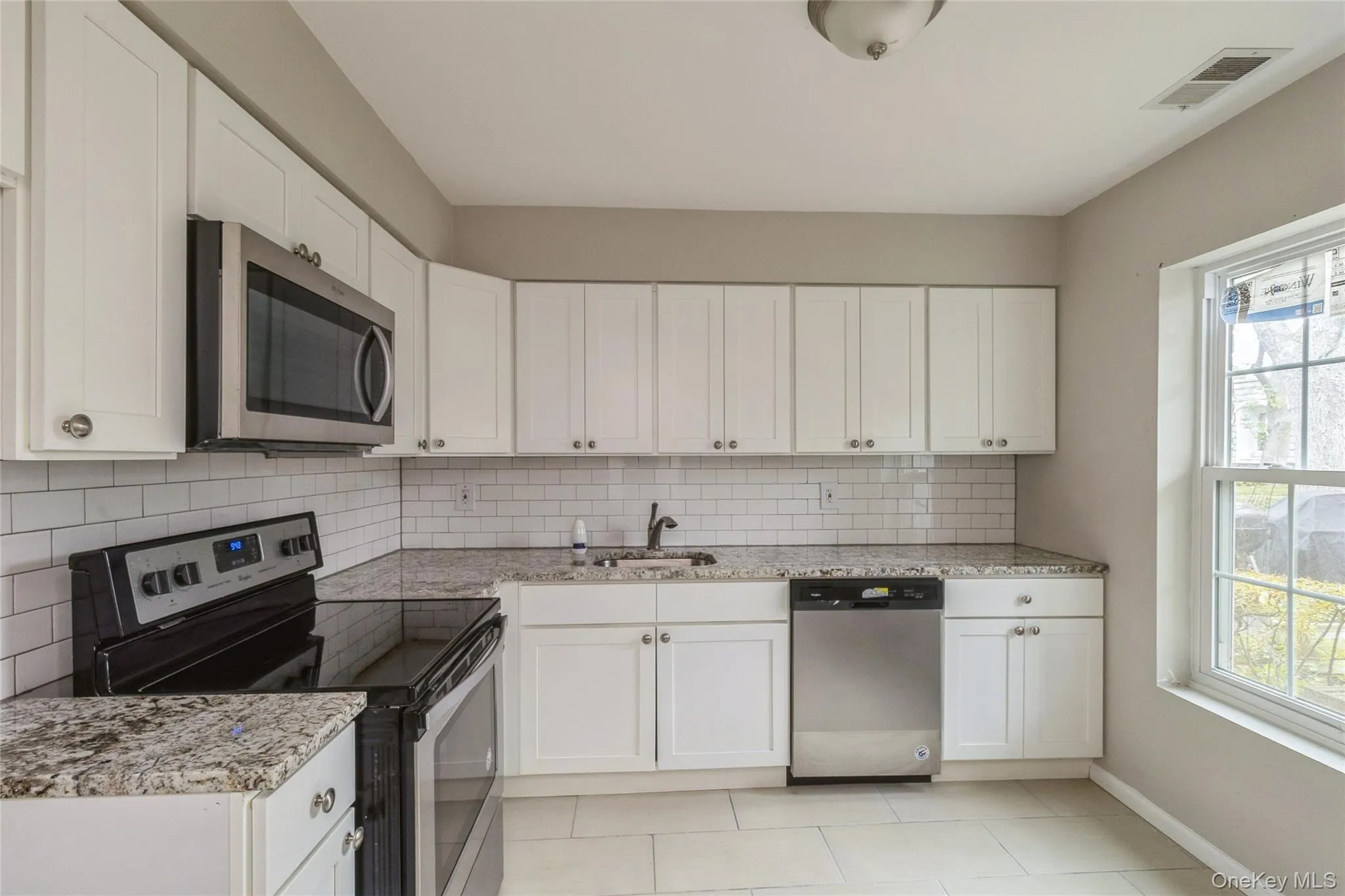 Kitchen with stainless steel appliances, white cabinetry, and light stone counters Kitchen with stainless steel appliances, white cabinetry, and light stone counters