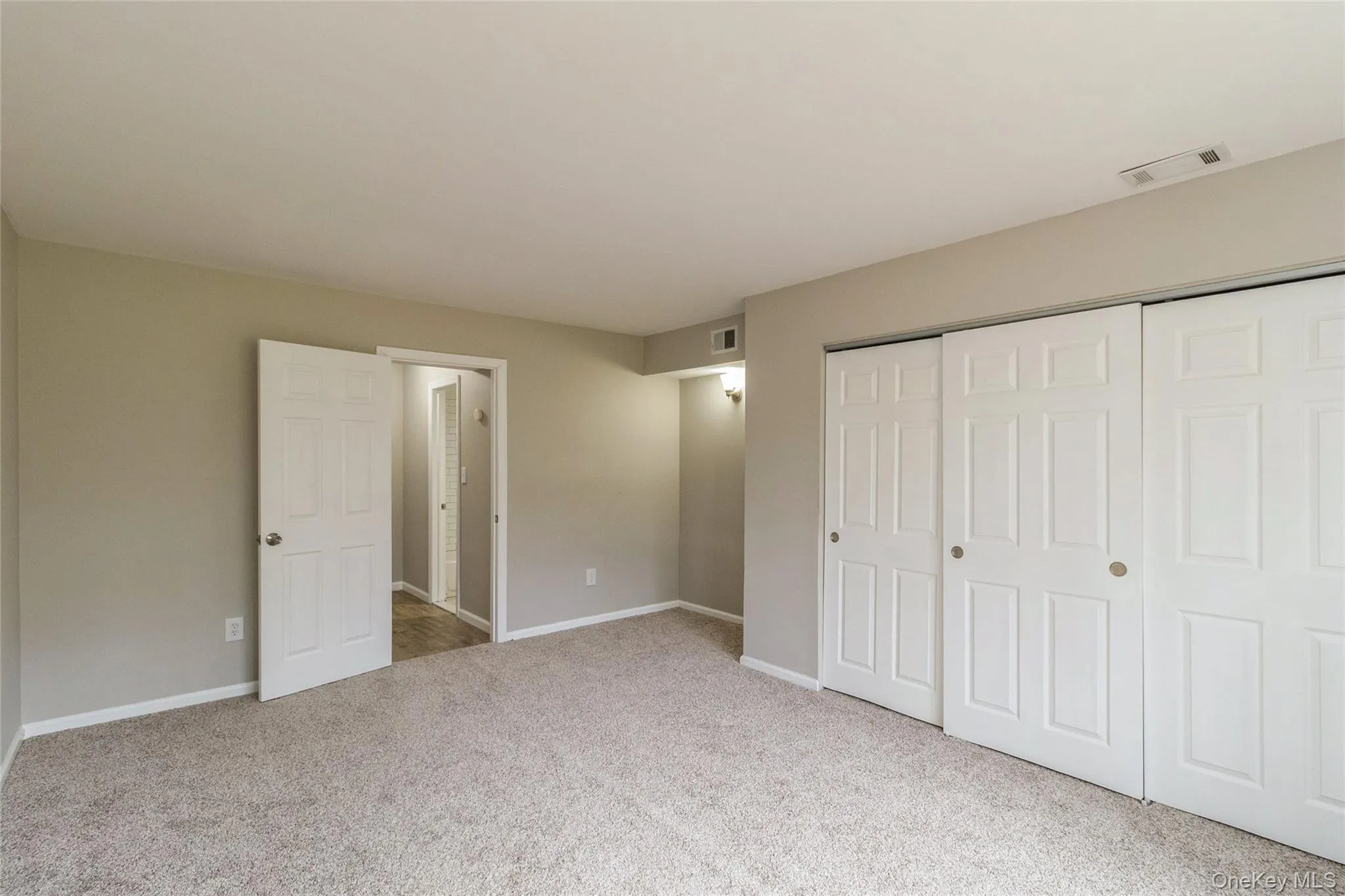 Unfurnished bedroom with a closet and light colored carpet Unfurnished bedroom with a closet and light colored carpet