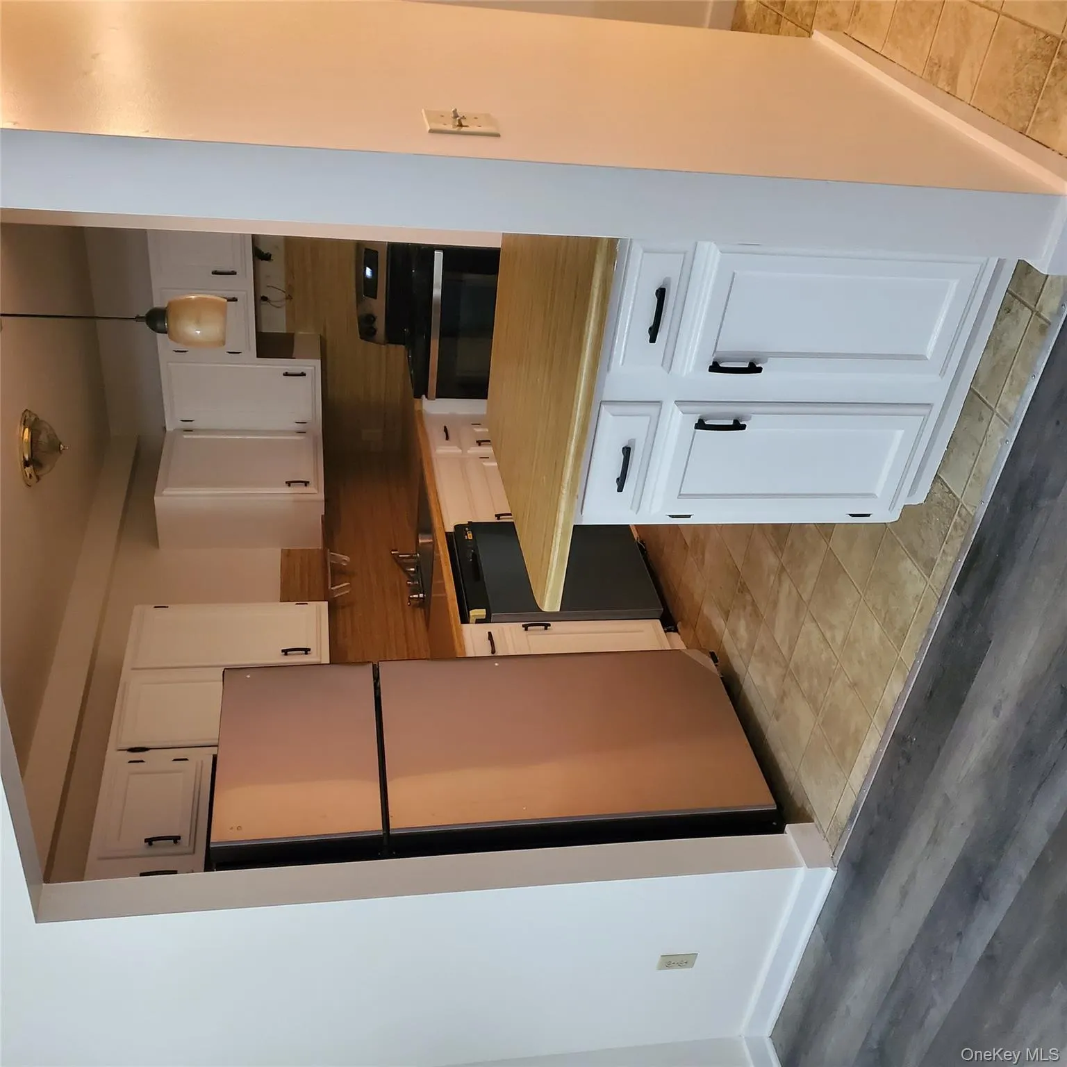 Kitchen featuring light countertops, appliances with stainless steel finishes, white cabinetry, pendant lighting, and backsplash Kitchen featuring light countertops, appliances with stainless steel finishes, white cabinetry, pendant lighting, and backsplash