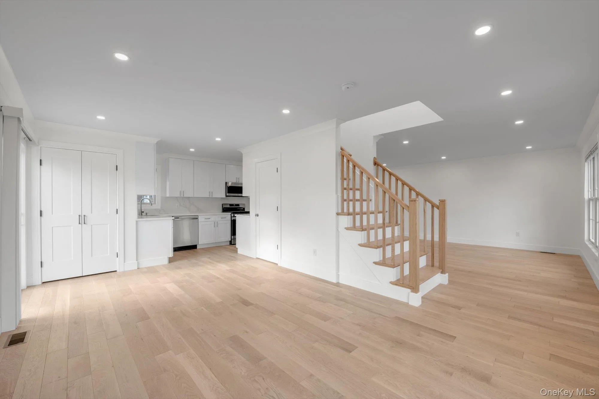 Unfurnished living room featuring light wood-style floors, stairs, and recessed lighting Unfurnished living room featuring light wood-style floors, stairs, and recessed lighting