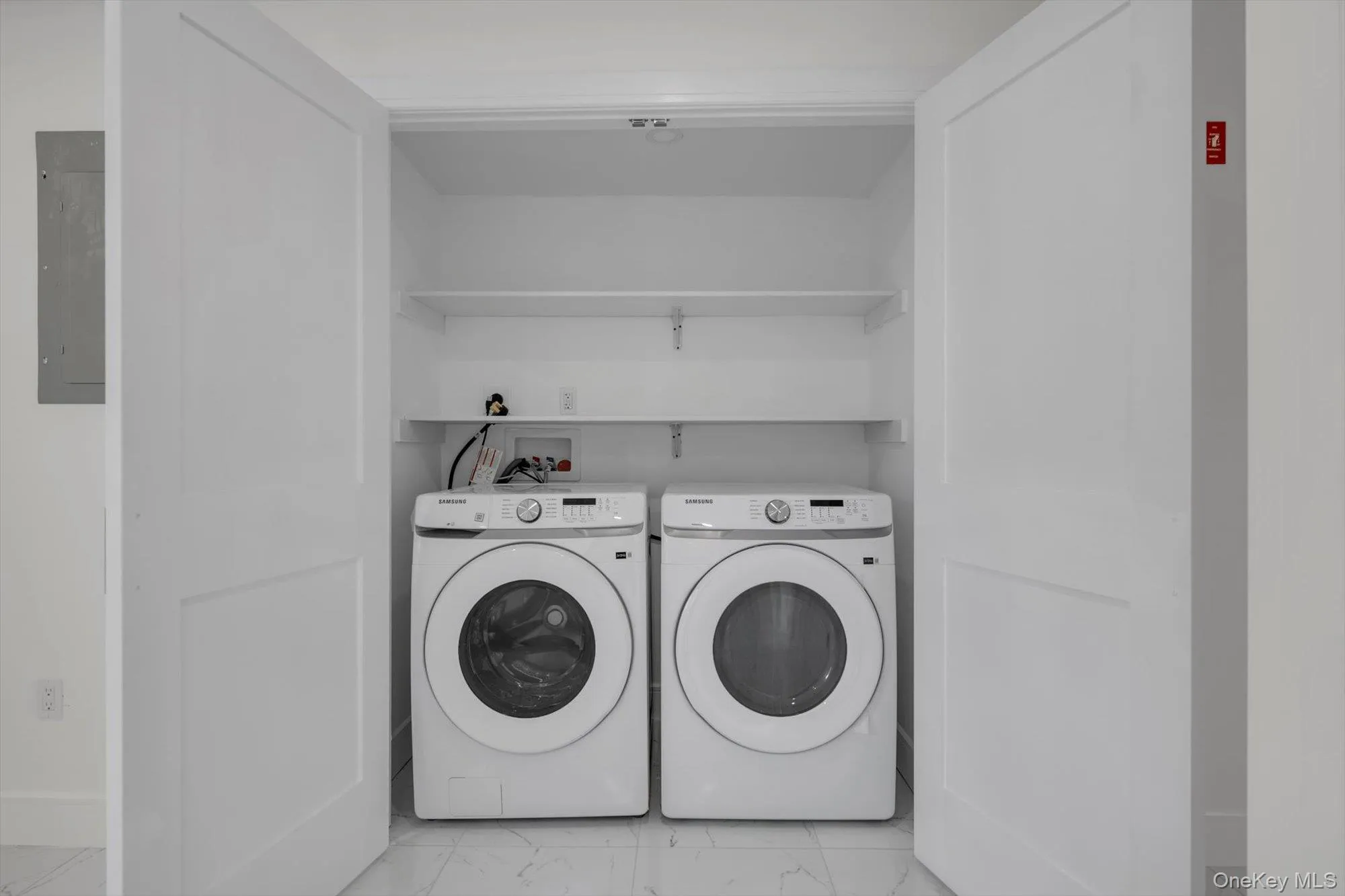 Washroom featuring light marble finish floors, washer and dryer, and electric panel Washroom featuring light marble finish floors, washer and dryer, and electric panel