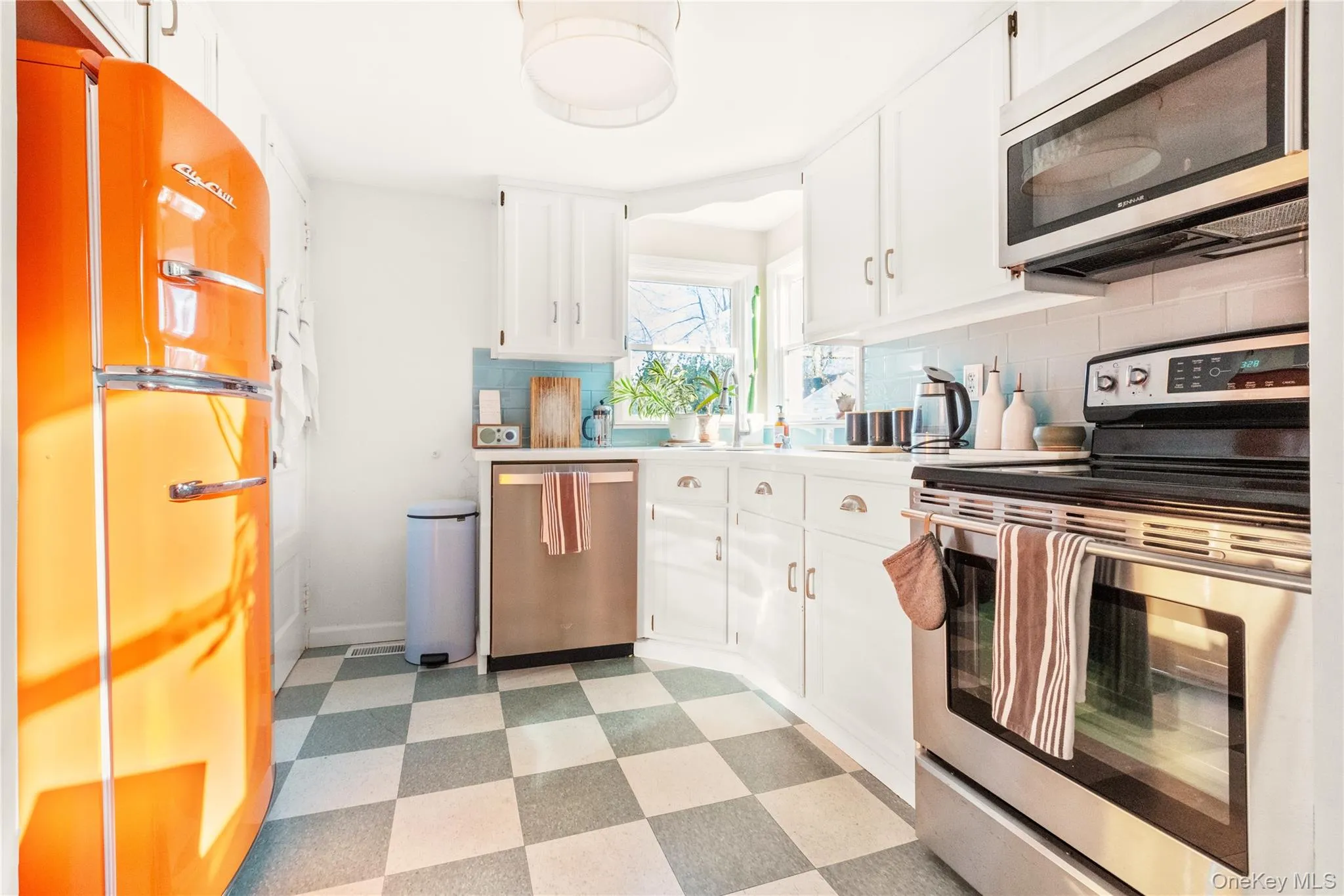 Kitchen featuring light flooring, appliances with stainless steel finishes, light countertops, tasteful backsplash, and white cabinetry Kitchen featuring light flooring, appliances with stainless steel finishes, light countertops, tasteful backsplash, and white cabinetry