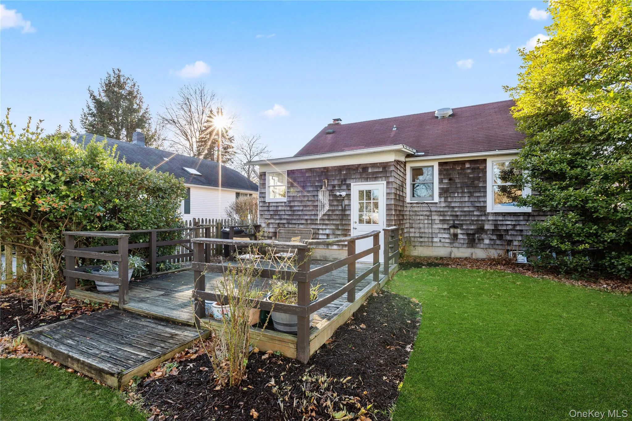Rear view of property featuring a deck, a lawn, and a shingled roof Rear view of property featuring a deck, a lawn, and a shingled roof