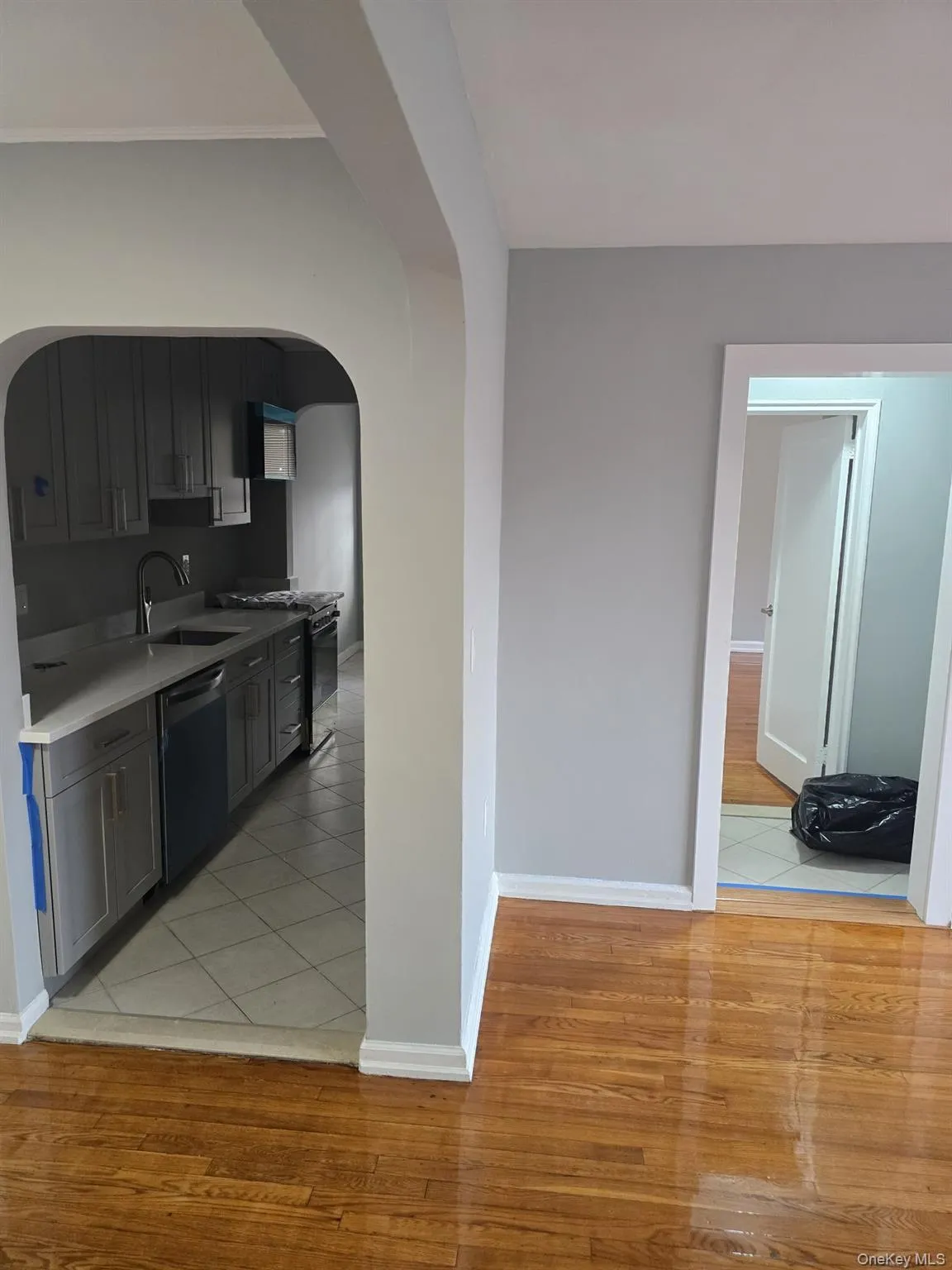 Kitchen with arched walkways, light wood-style flooring, gas range, dishwasher, and light countertops Kitchen with arched walkways, light wood-style flooring, gas range, dishwasher, and light countertops