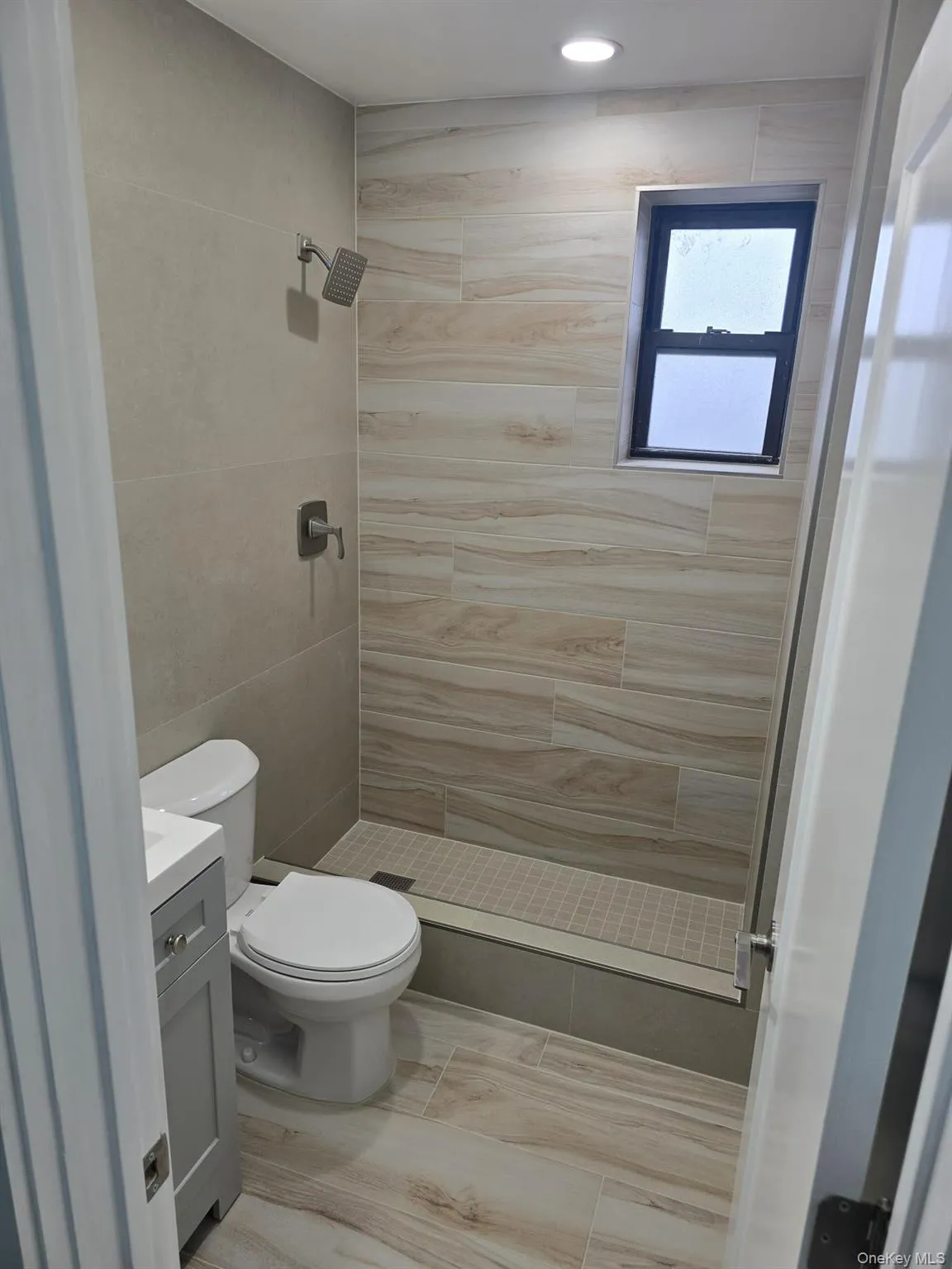 Bathroom with a shower stall, vanity, and tile walls Bathroom with a shower stall, vanity, and tile walls