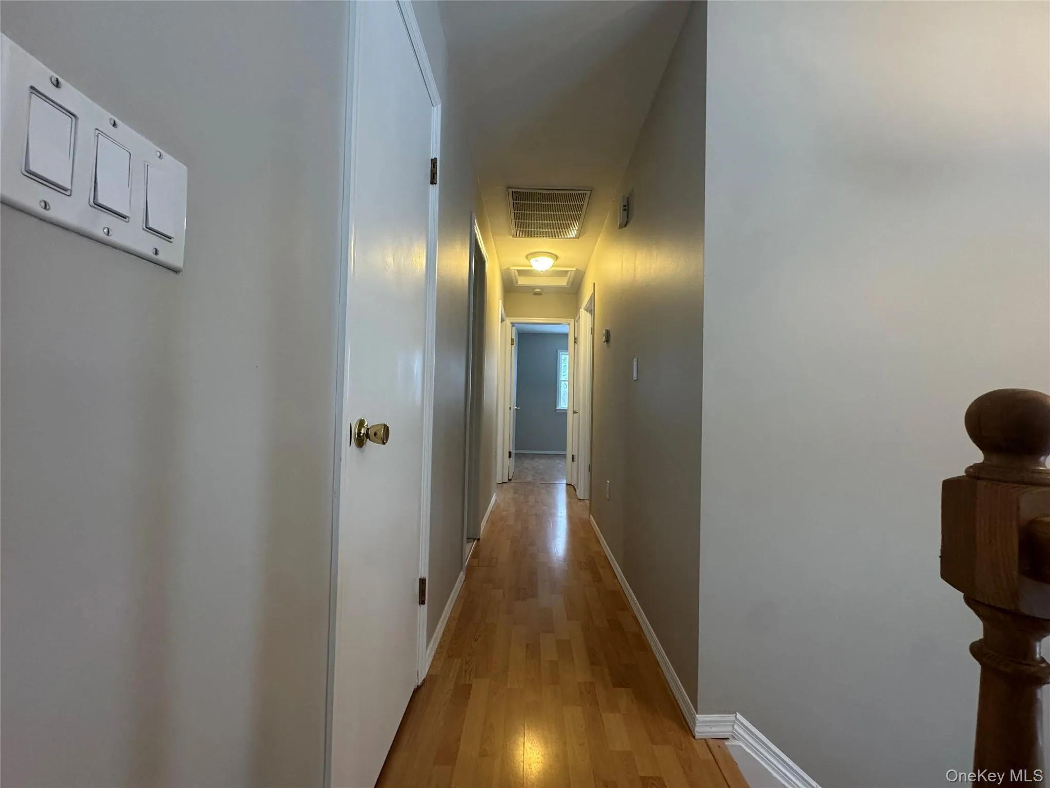 Corridor featuring light wood-style flooring and attic access Corridor featuring light wood-style flooring and attic access