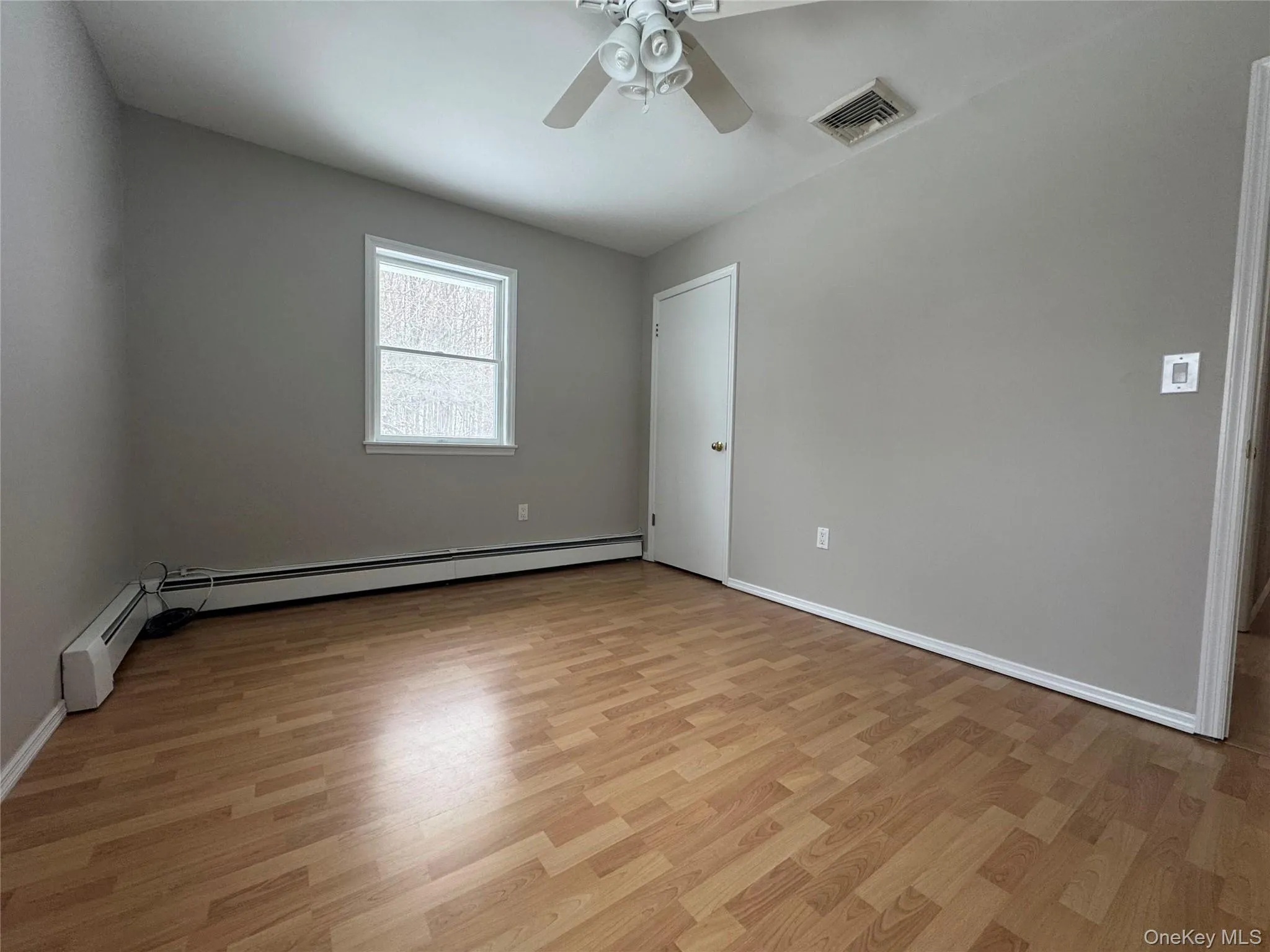 Spare room featuring light wood-style floors, a baseboard radiator, and a ceiling fan Spare room featuring light wood-style floors, a baseboard radiator, and a ceiling fan