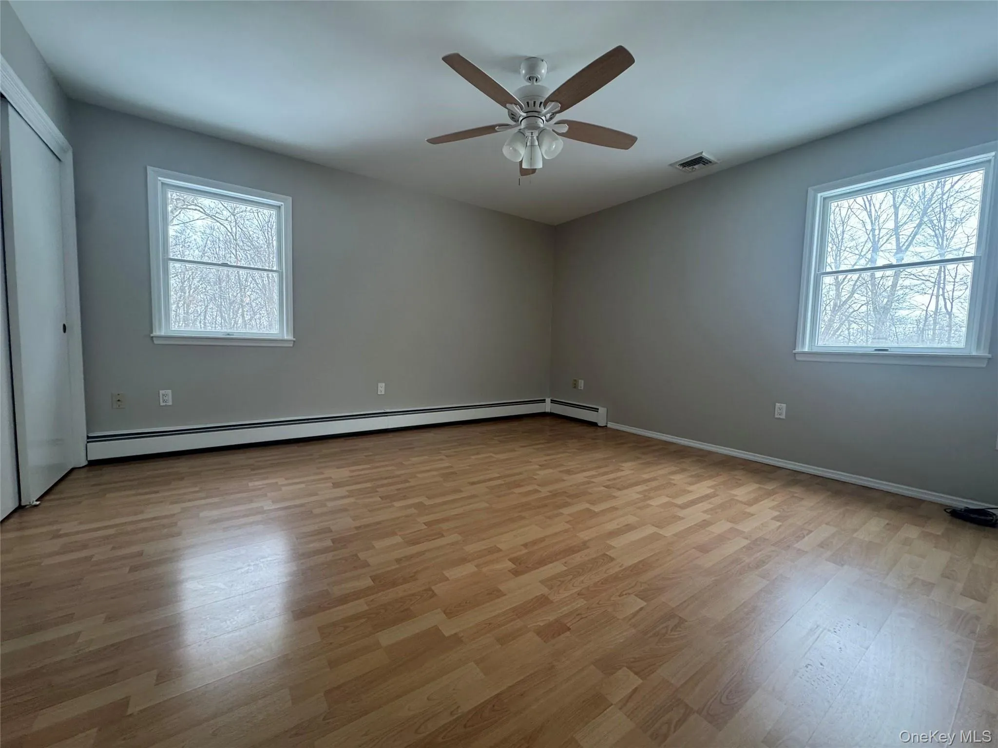 Unfurnished room featuring light wood-style flooring, healthy amount of natural light, and a ceiling fan Unfurnished room featuring light wood-style flooring, healthy amount of natural light, and a ceiling fan