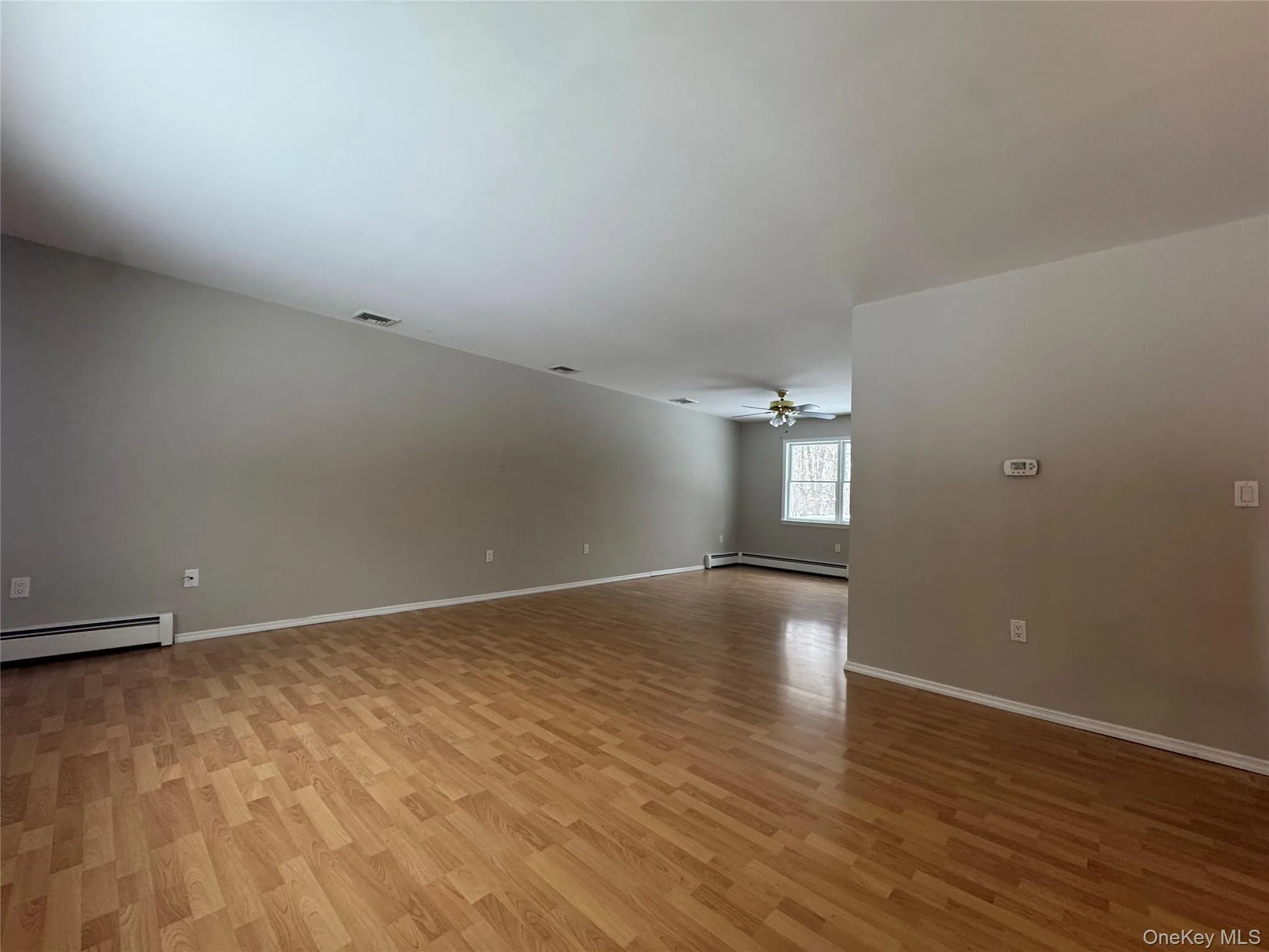 Unfurnished room featuring light wood-style floors, a baseboard heating unit, and a ceiling fan Unfurnished room featuring light wood-style floors, a baseboard heating unit, and a ceiling fan