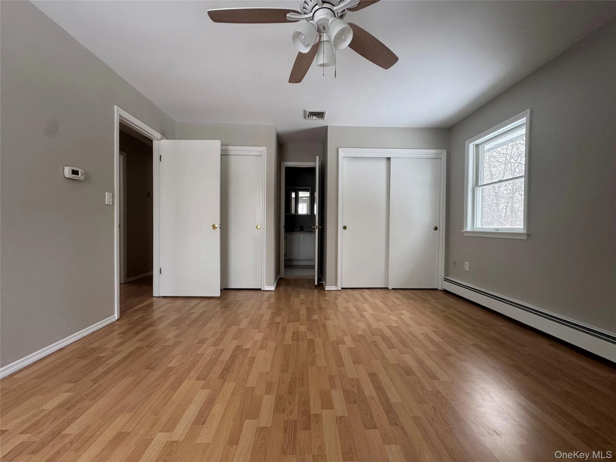 Unfurnished bedroom with two closets, light wood-style floors, ceiling fan, and ensuite bath Unfurnished bedroom with two closets, light wood-style floors, ceiling fan, and ensuite bath
