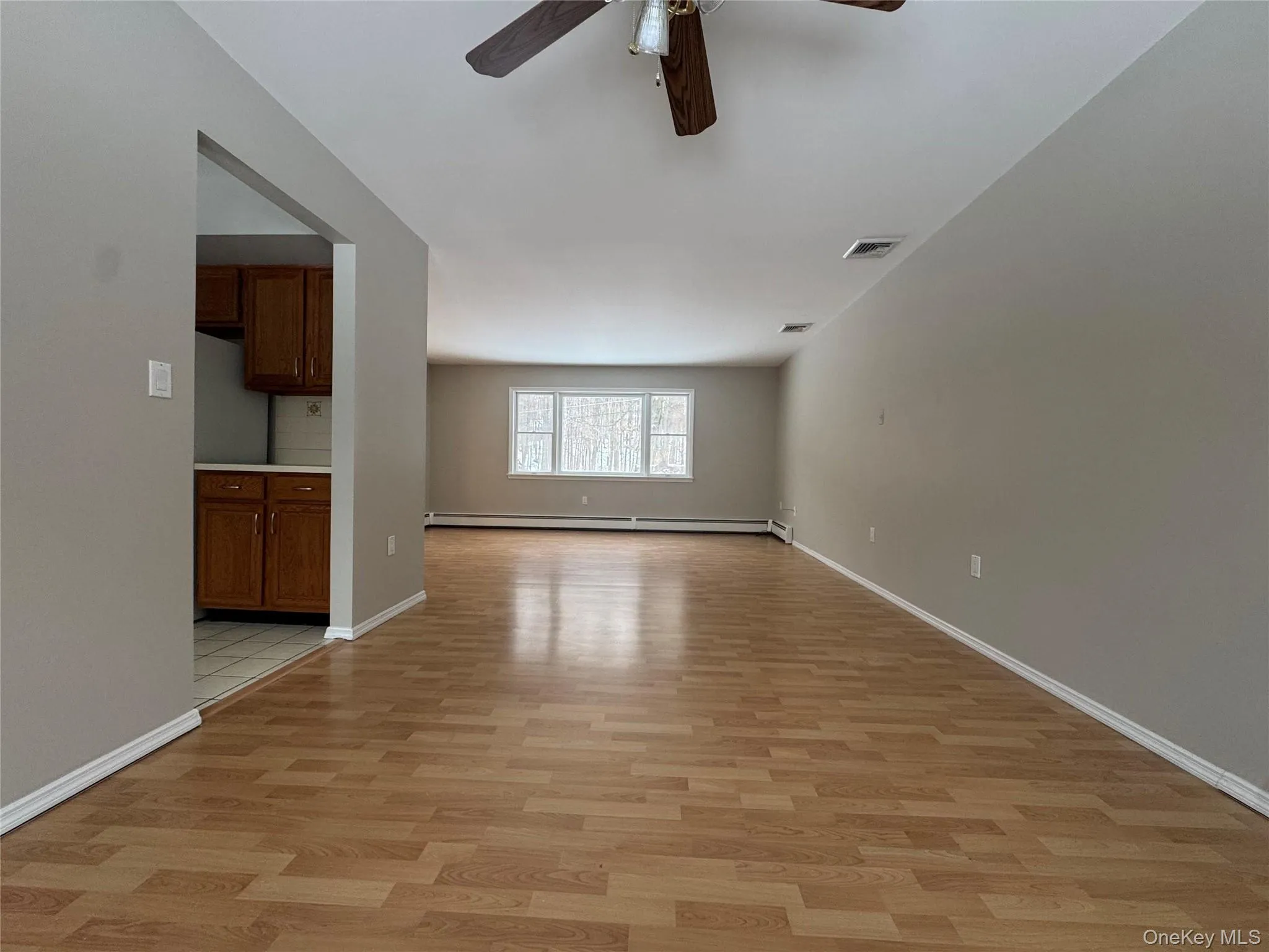 Unfurnished room with light wood-style flooring, a ceiling fan, and a baseboard heating unit Unfurnished room with light wood-style flooring, a ceiling fan, and a baseboard heating unit