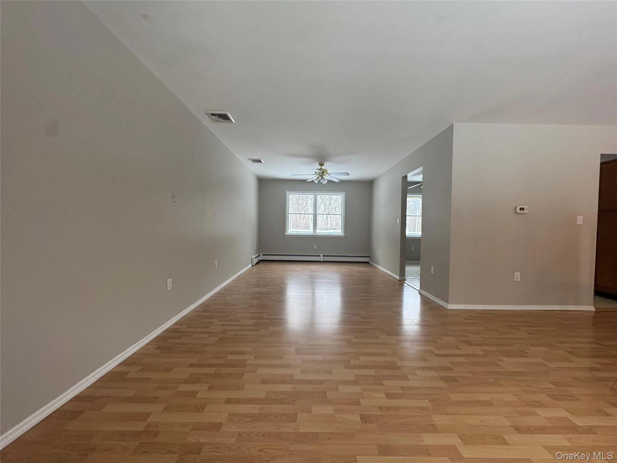 Empty room with light wood finished floors, a baseboard heating unit, and ceiling fan Empty room with light wood finished floors, a baseboard heating unit, and ceiling fan