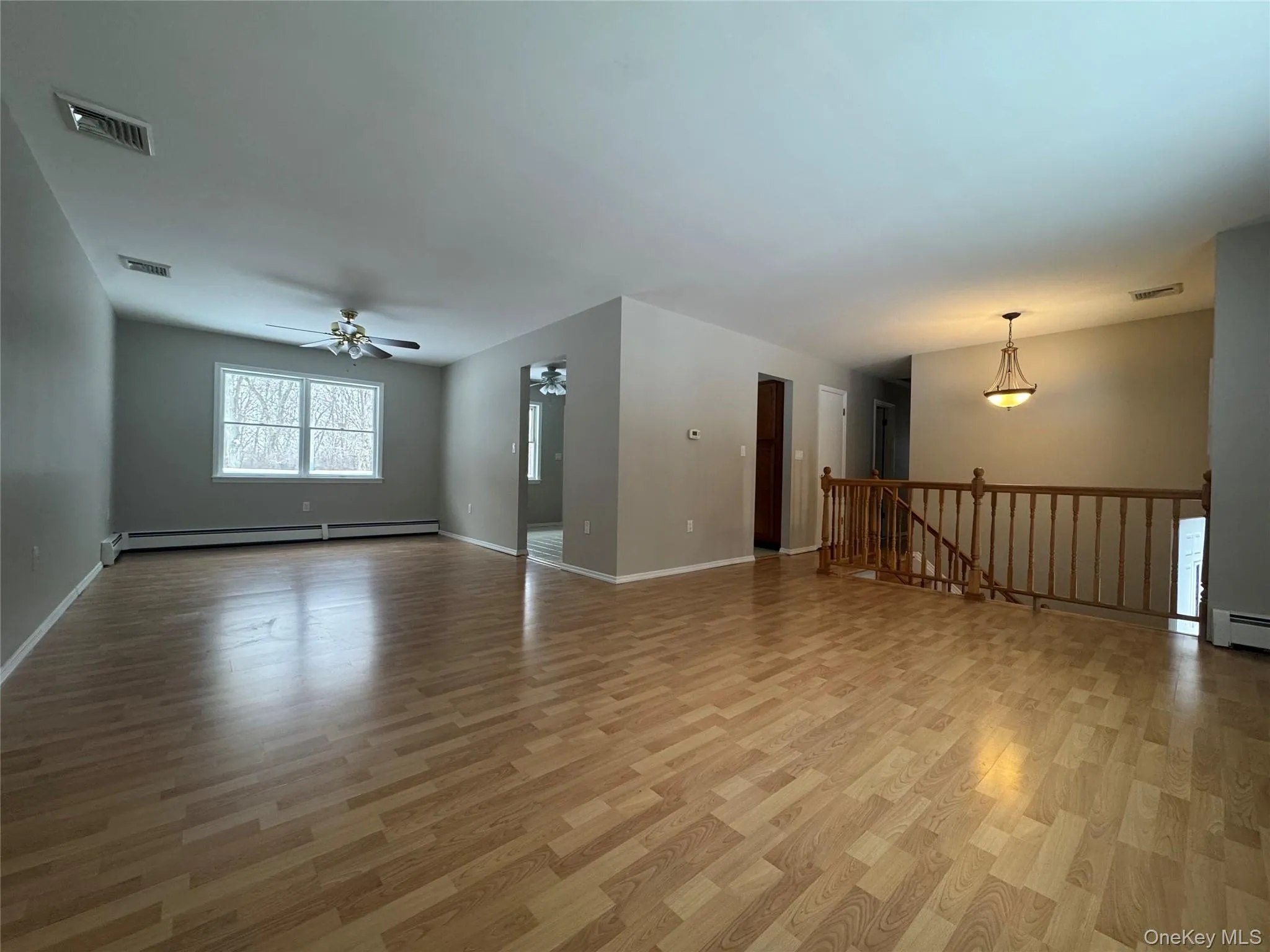 Unfurnished living room featuring light wood-style flooring, a baseboard heating unit, and a ceiling fan Unfurnished living room featuring light wood-style flooring, a baseboard heating unit, and a ceiling fan