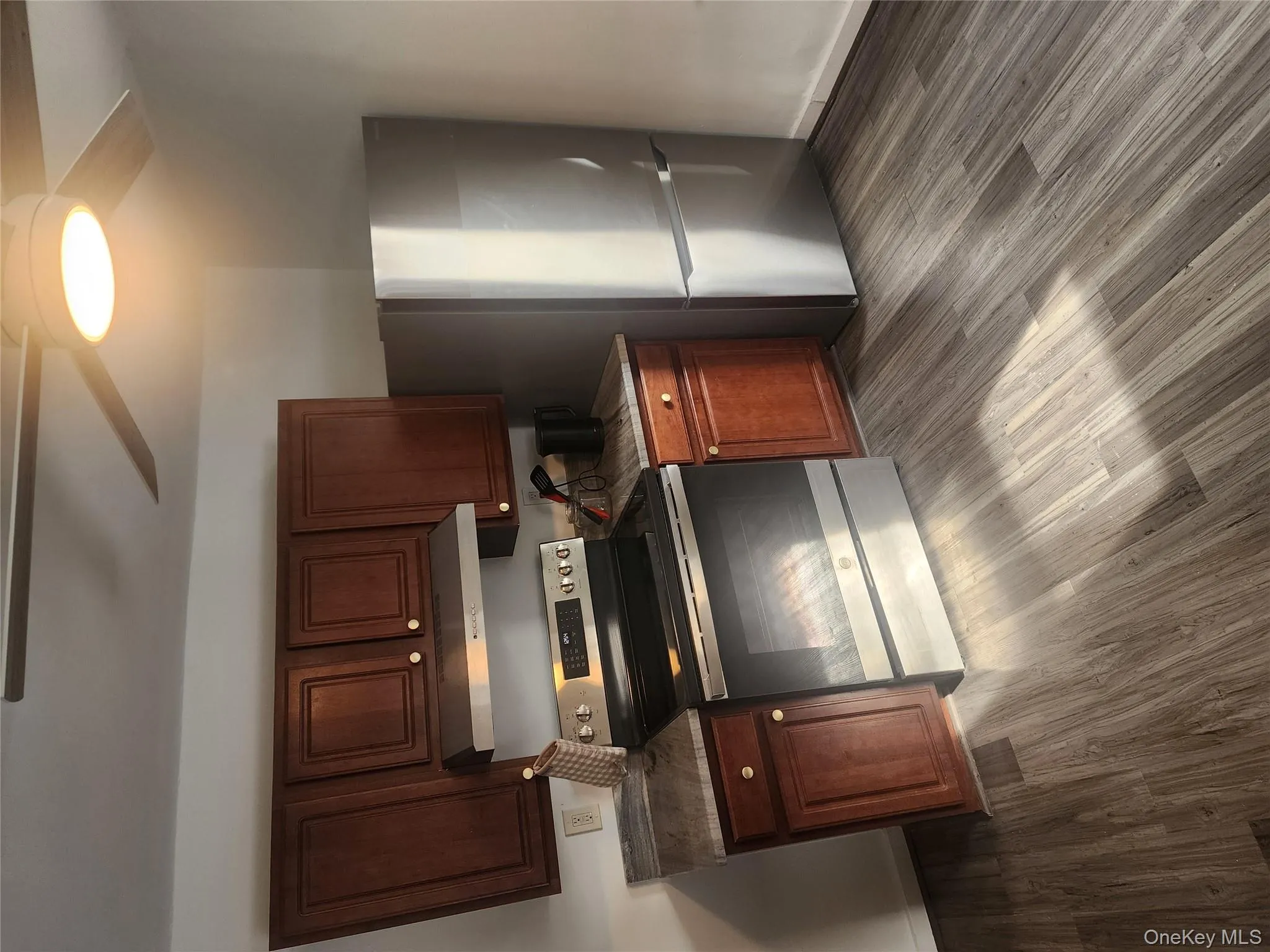 Kitchen with appliances with stainless steel finishes, extractor fan, a ceiling fan, and dark wood-style floors Kitchen with appliances with stainless steel finishes, extractor fan, a ceiling fan, and dark wood-style floors