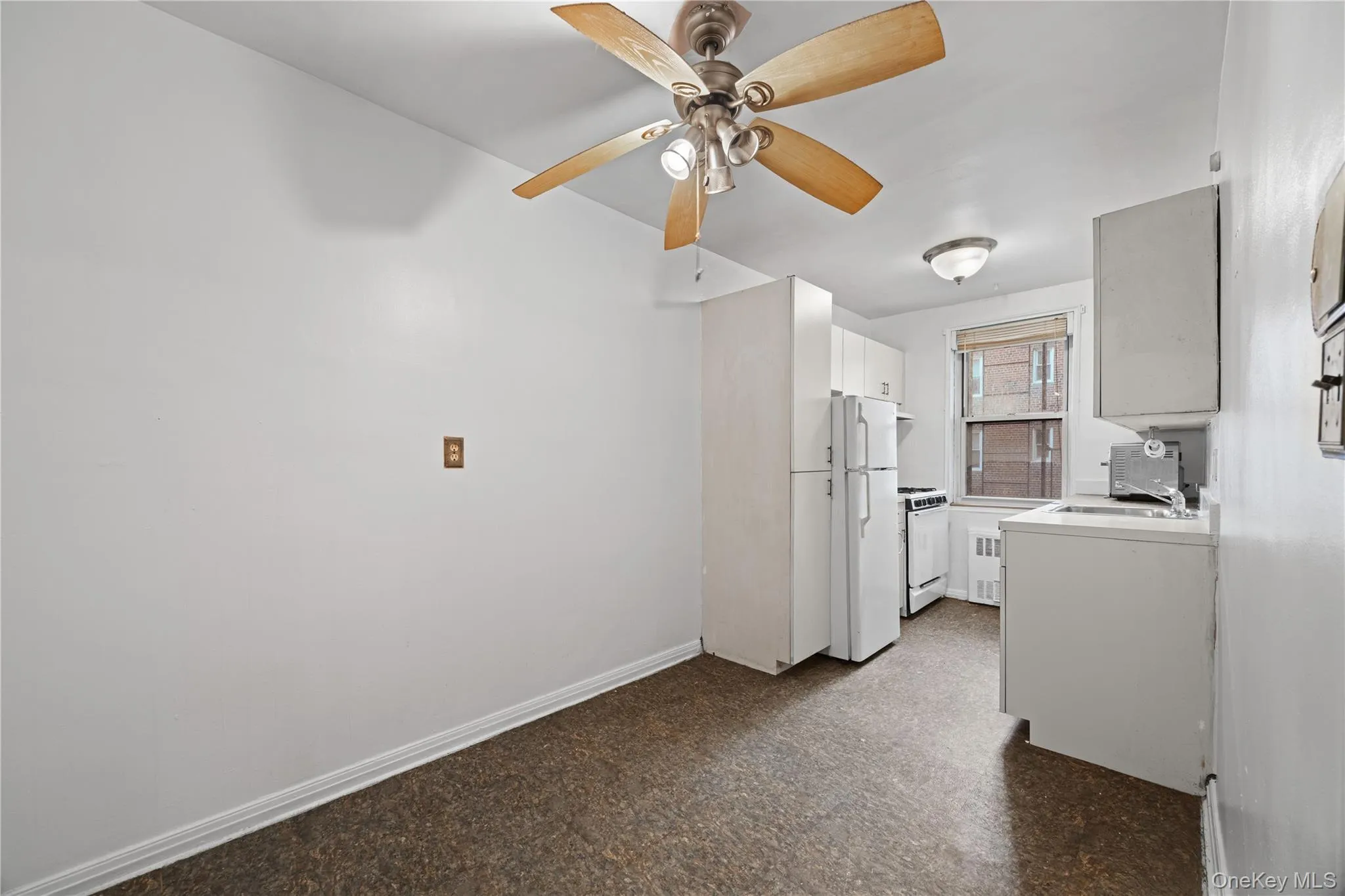 Kitchen featuring white cabinetry, white appliances, ceiling fan, light countertops, and dark flooring Kitchen featuring white cabinetry, white appliances, ceiling fan, light countertops, and dark flooring