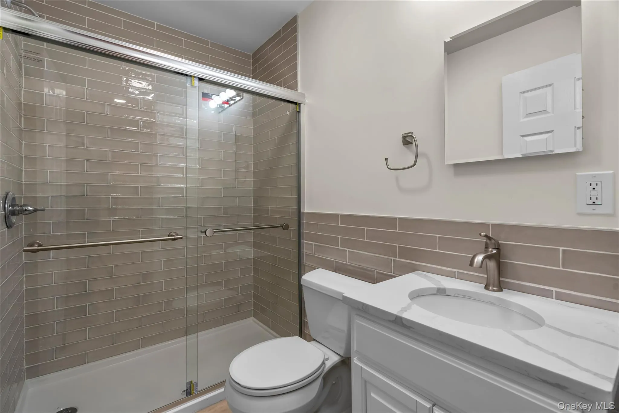 Bathroom featuring a shower with door, toilet, tile walls, and vanity Bathroom featuring a shower with door, toilet, tile walls, and vanity