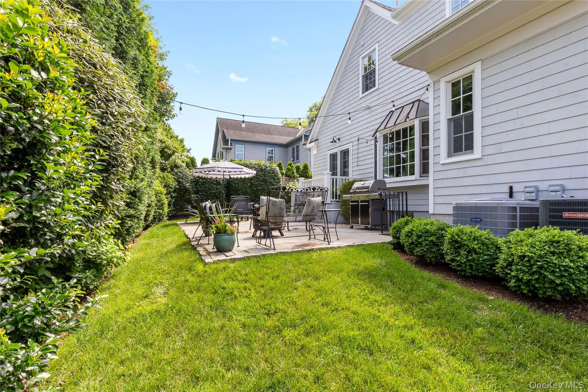 View of green lawn featuring a patio area View of green lawn featuring a patio area
