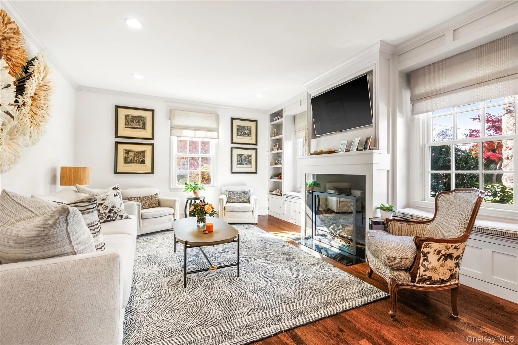 Living room with wood finished floors, ornamental molding, built in shelves, a large gas fireplace, and recessed lighting Living room with wood finished floors, ornamental molding, built in shelves, a large gas fireplace, and recessed lighting