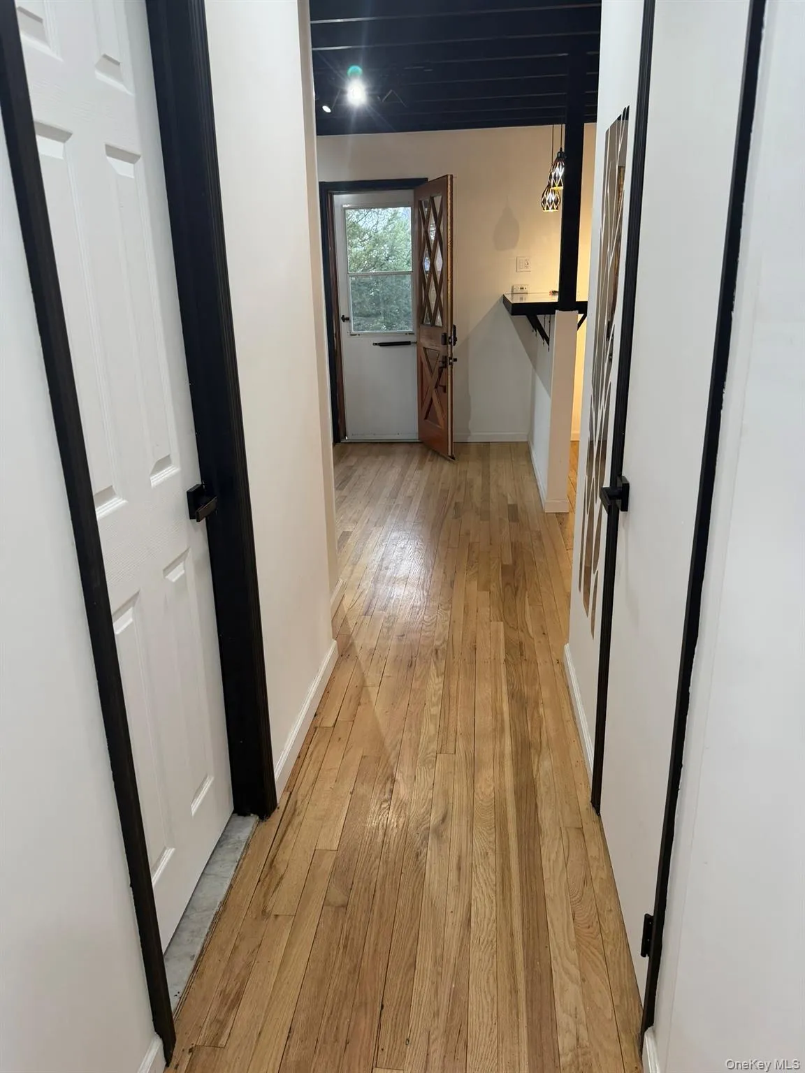 Hallway with light wood-style flooring and baseboards Hallway with light wood-style flooring and baseboards