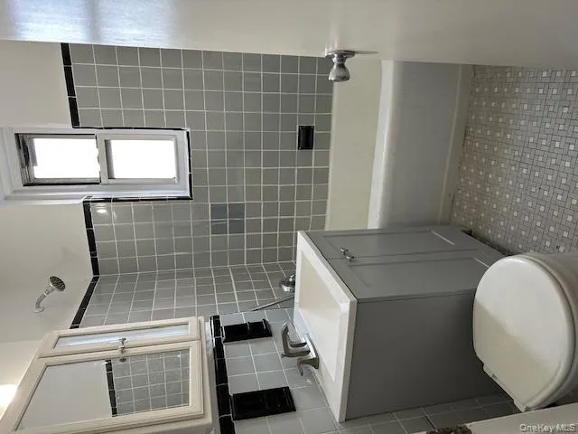 Bathroom with vanity, tile walls, and washtub / shower combination Bathroom with vanity, tile walls, and washtub / shower combination