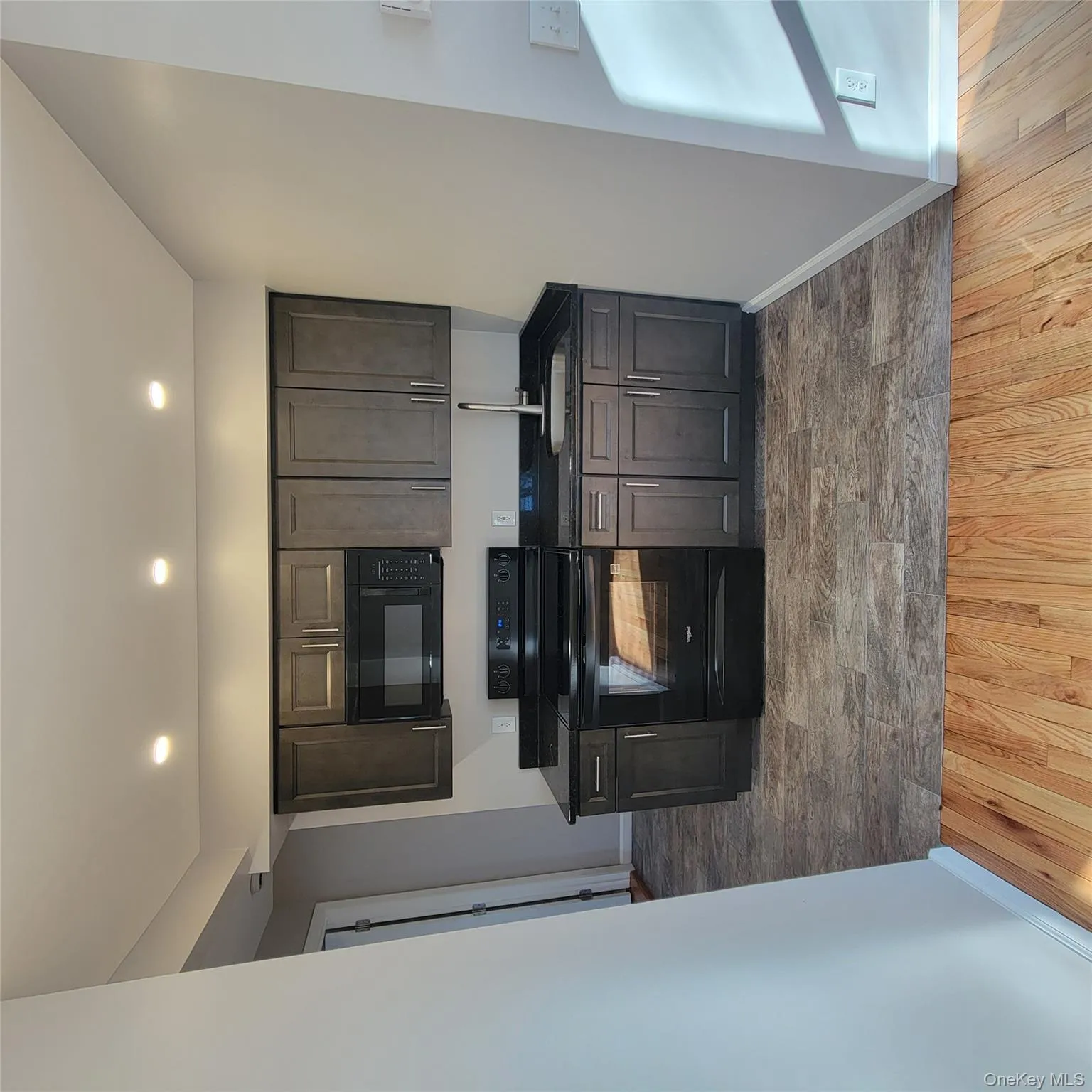 Kitchen with black range oven, stainless steel microwave, dark brown cabinetry, dark wood finished floors, and recessed lighting Kitchen with black range oven, stainless steel microwave, dark brown cabinetry, dark wood finished floors, and recessed lighting