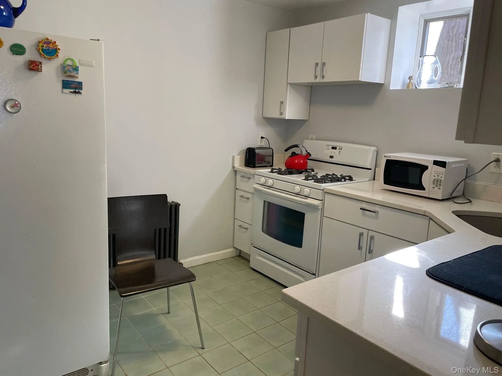 Kitchen featuring white appliances, white cabinets, light tile patterned floors, and light stone counters Kitchen featuring white appliances, white cabinets, light tile patterned floors, and light stone counters