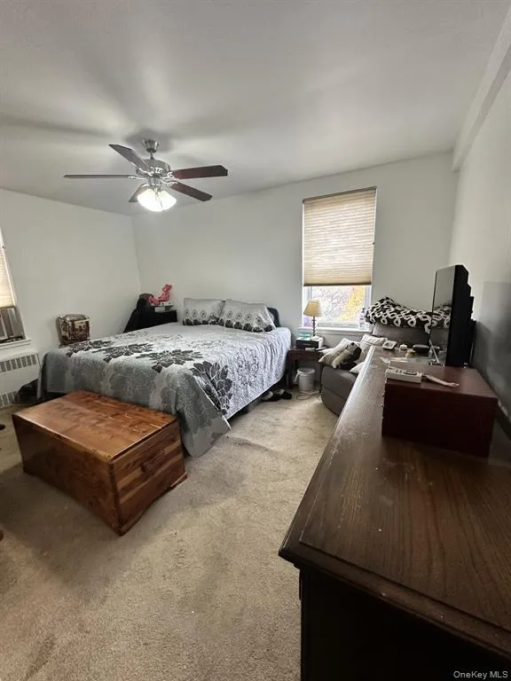 Bedroom with carpet, a ceiling fan, and radiator heating unit Bedroom with carpet, a ceiling fan, and radiator heating unit