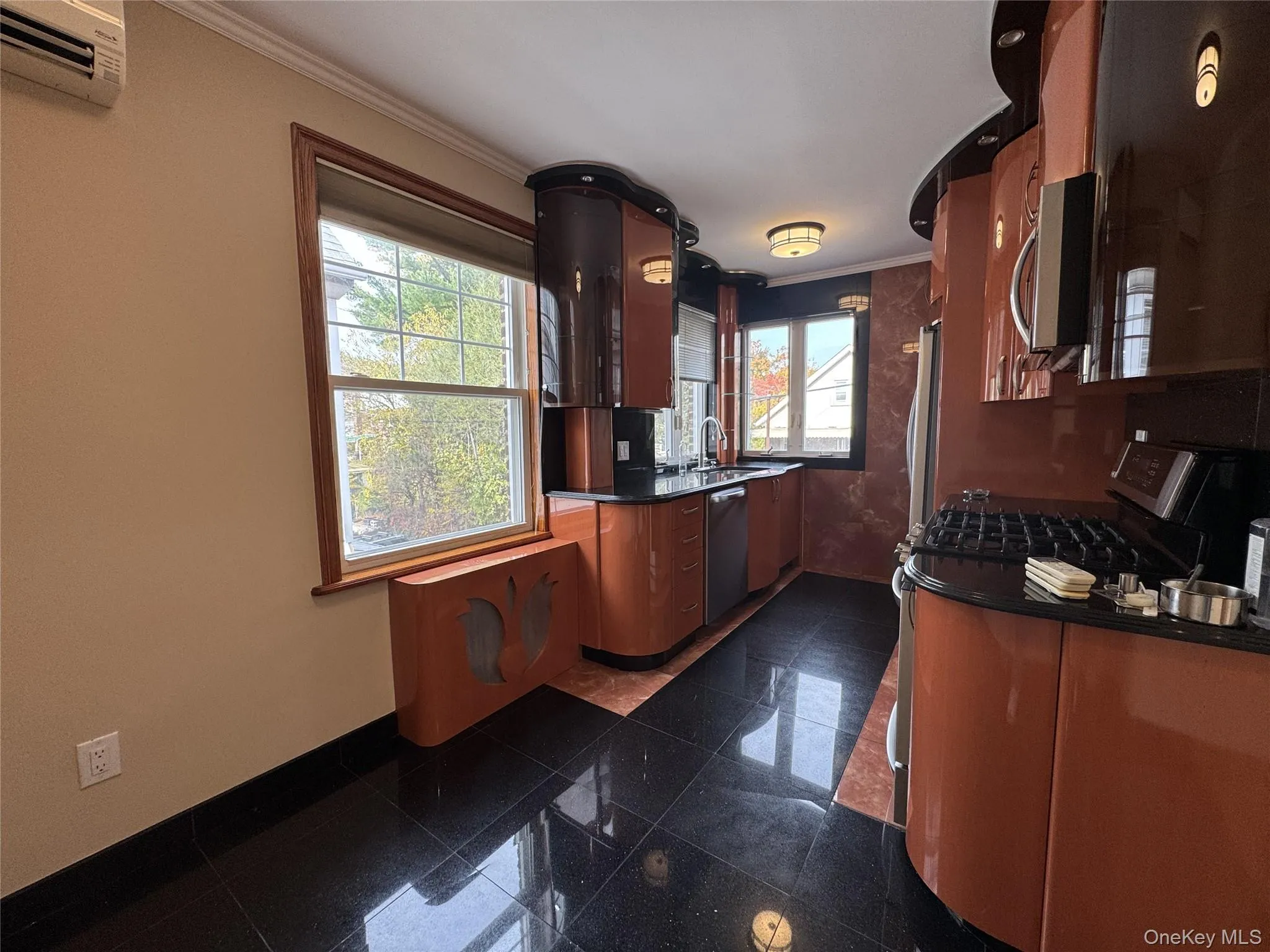 Kitchen with a wall mounted air conditioner, granite tiled floors, stainless steel appliances, and ornamental molding Kitchen with a wall mounted air conditioner, granite tiled floors, stainless steel appliances, and ornamental molding