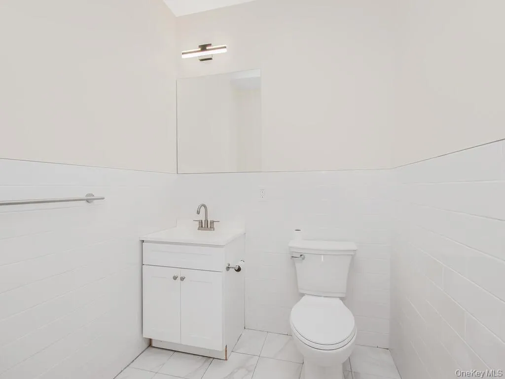 Bathroom with a wainscoted wall, tile walls, and vanity Bathroom with a wainscoted wall, tile walls, and vanity