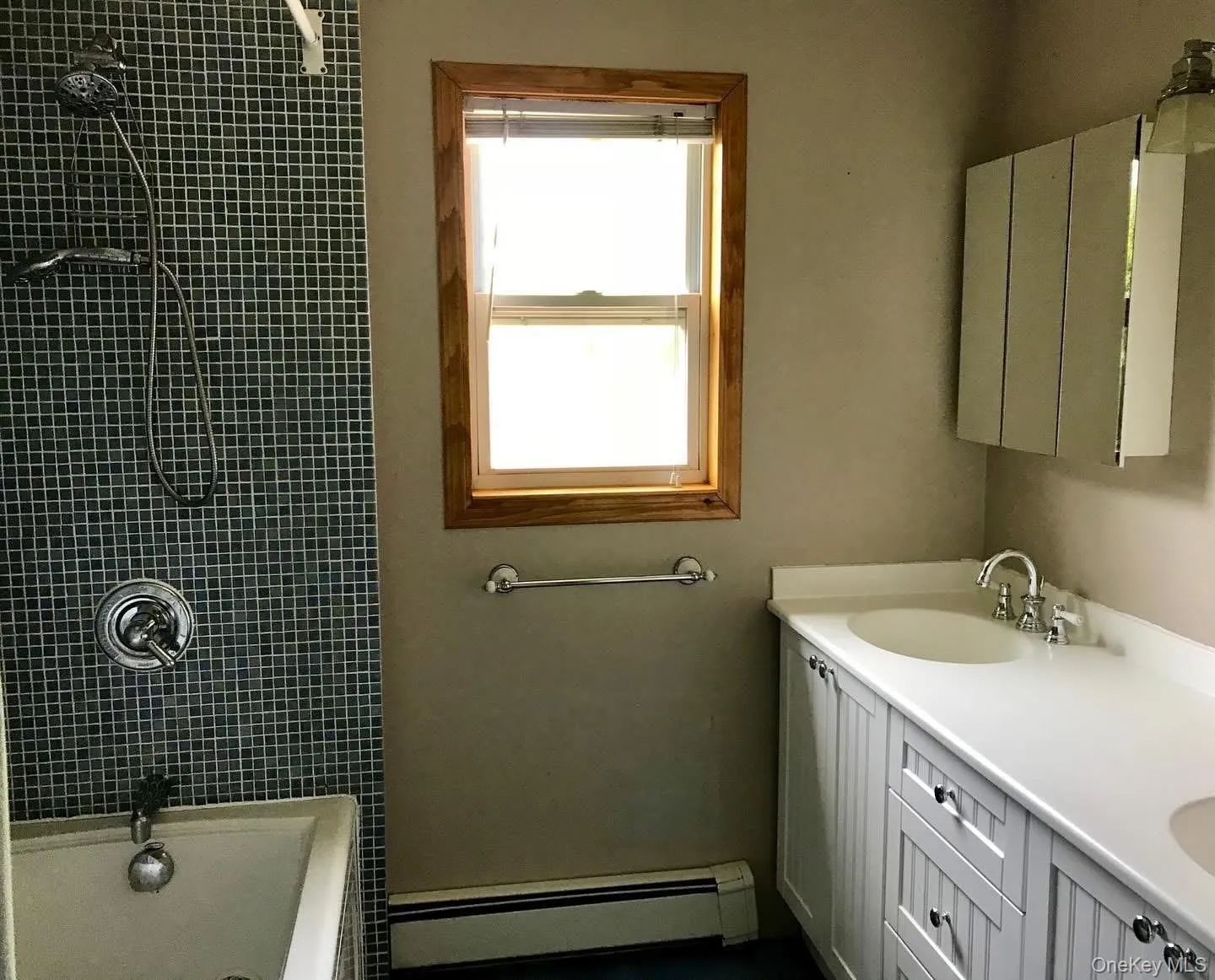 Full bathroom with double vanity, a baseboard radiator, and bathing tub / shower combination Full bathroom with double vanity, a baseboard radiator, and bathing tub / shower combination