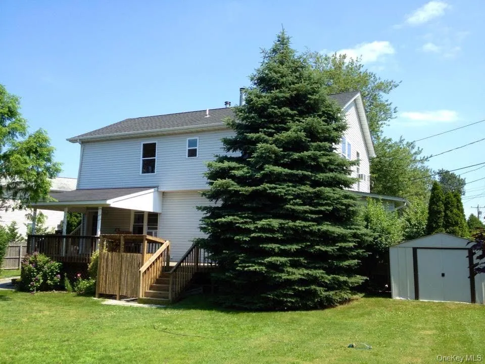 Back of house with a storage unit, a yard, a wooden deck, and stairway Back of house with a storage unit, a yard, a wooden deck, and stairway
