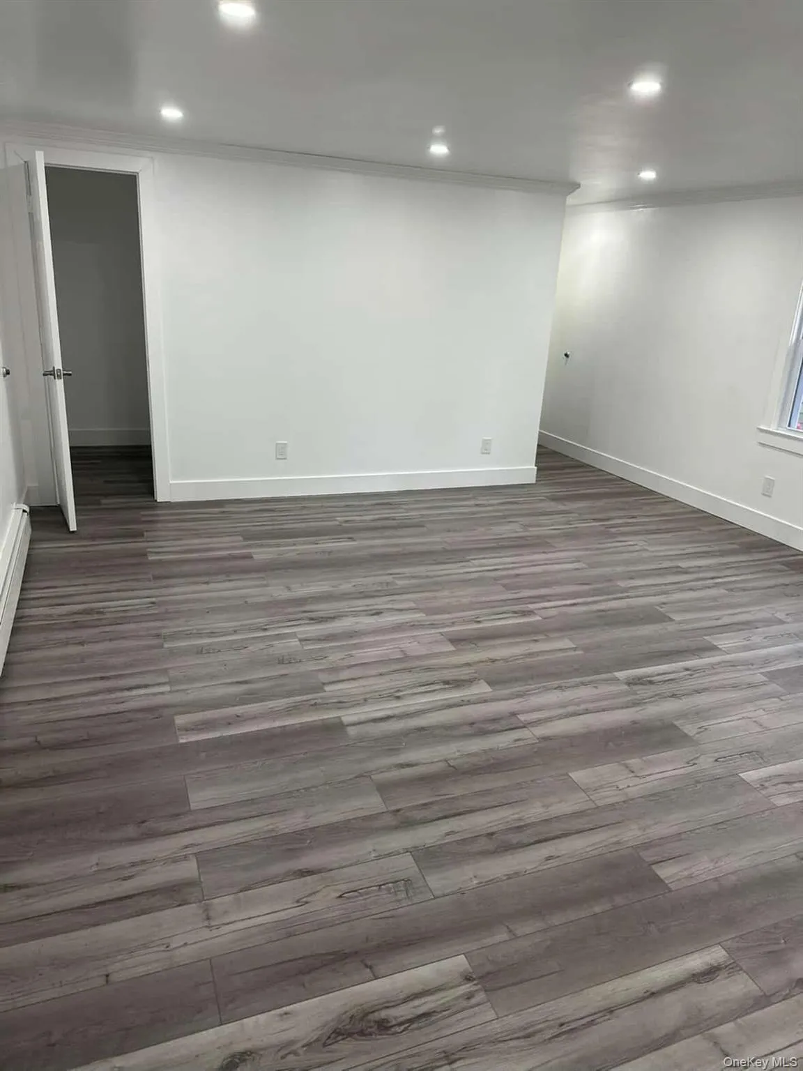 with wood finished floors, recessed lighting, and a baseboard heating unit with wood finished floors, recessed lighting, and a baseboard heating unit