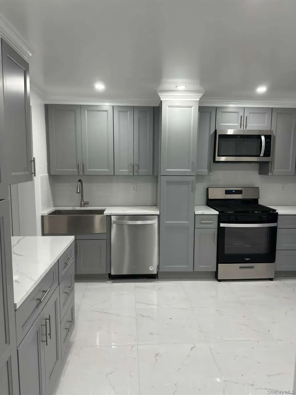 Kitchen featuring gray cabinetry, stainless steel appliances, light marble finish floors, light stone countertops, and recessed lighting Kitchen featuring gray cabinetry, stainless steel appliances, light marble finish floors, light stone countertops, and recessed lighting