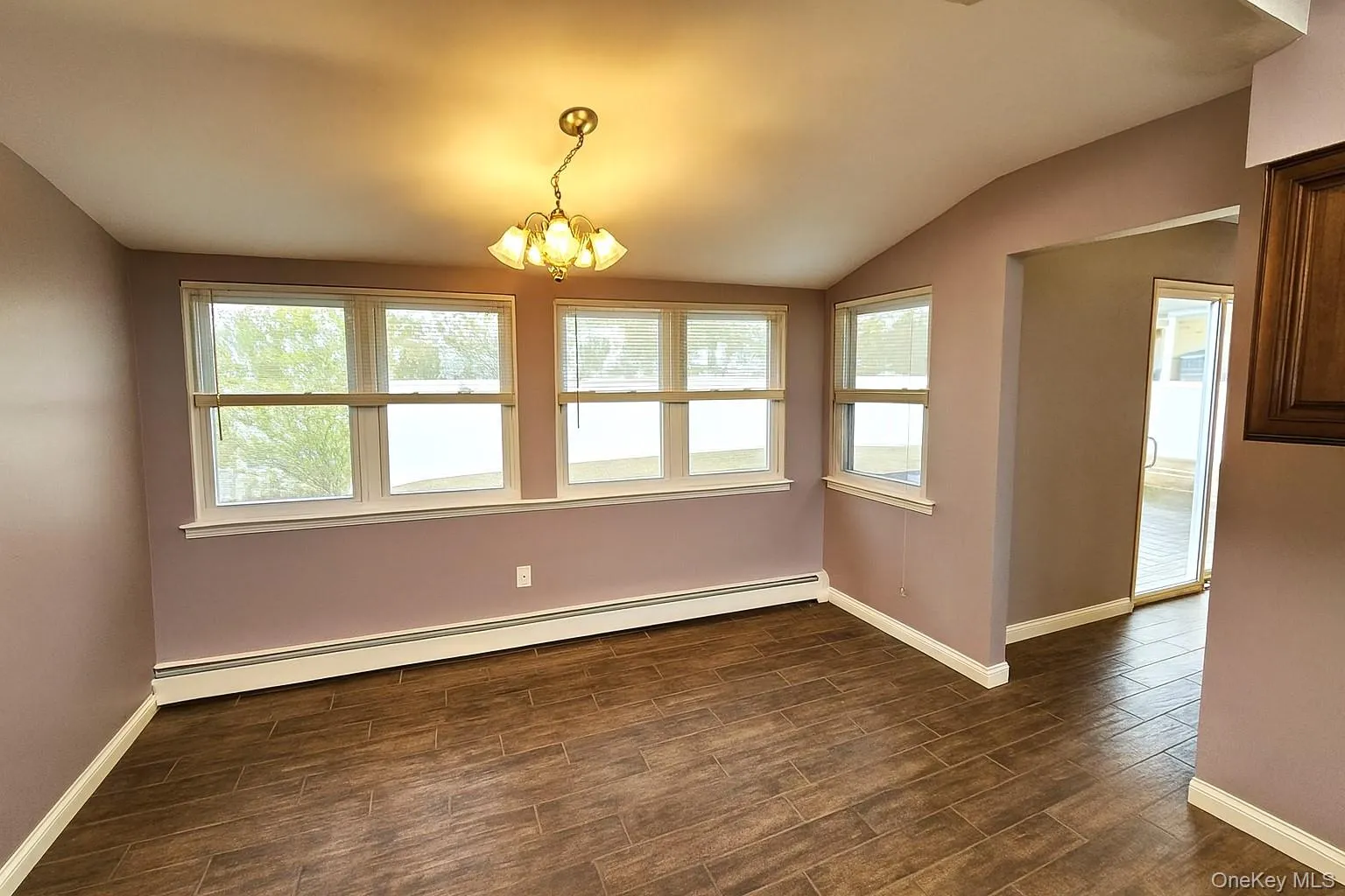 Unfurnished dining area featuring a baseboard radiator, a chandelier, wood finish floors, and vaulted ceiling Unfurnished dining area featuring a baseboard radiator, a chandelier, wood finish floors, and vaulted ceiling