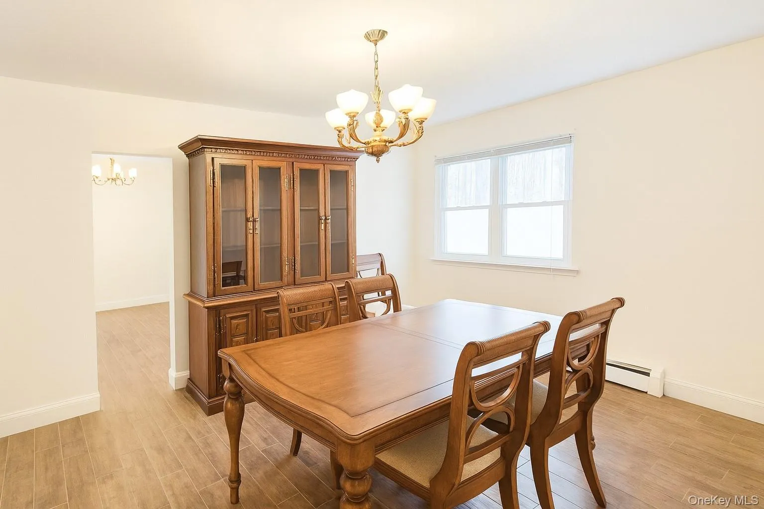 Dining area with a chandelier, light wood-style flooring, and baseboard heating Dining area with a chandelier, light wood-style flooring, and baseboard heating