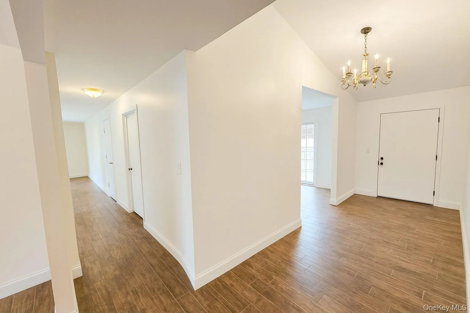 Foyer with wood finished floors, a chandelier, and vaulted ceiling Foyer with wood finished floors, a chandelier, and vaulted ceiling