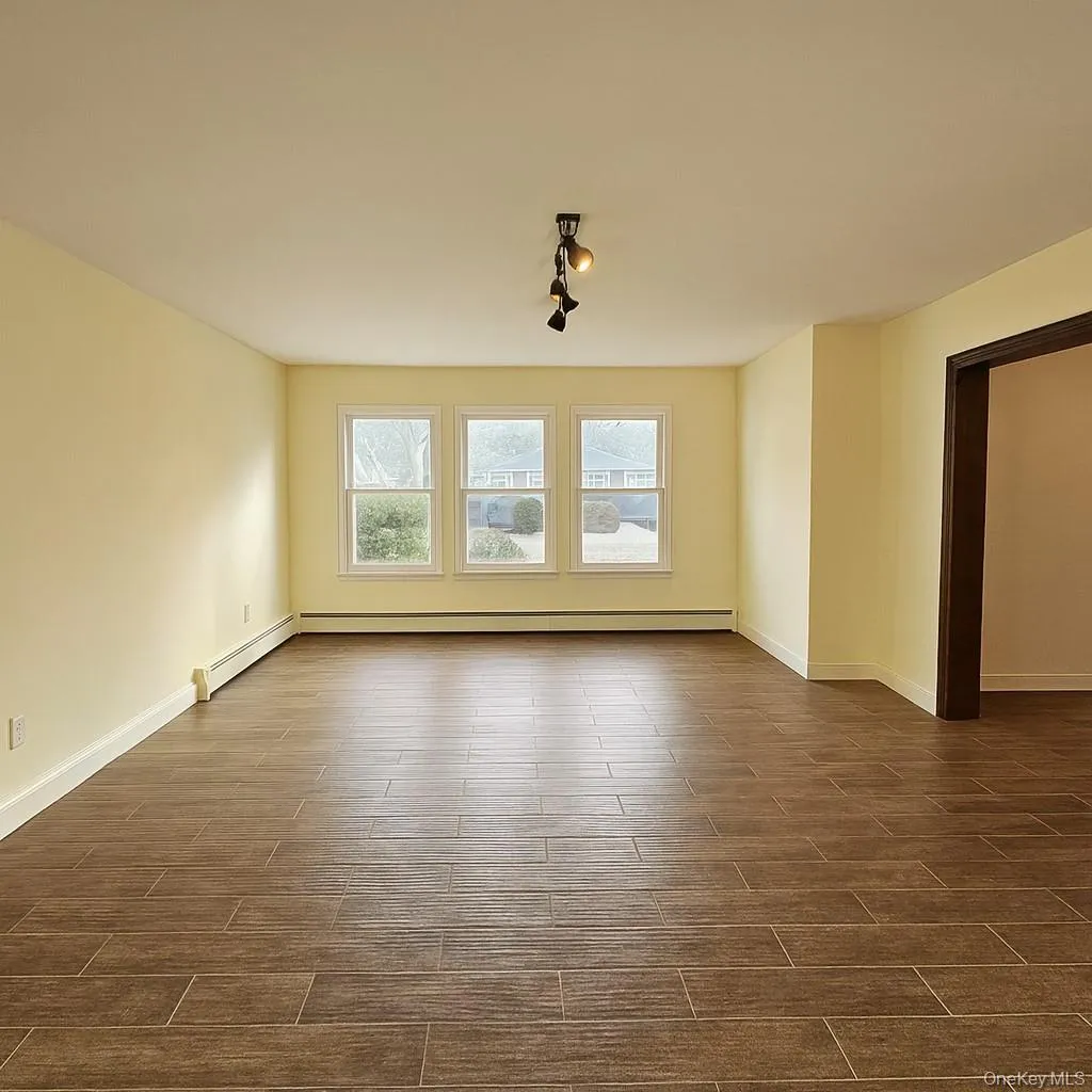 Empty room featuring wood tiled floors and a baseboard heating unit Empty room featuring wood tiled floors and a baseboard heating unit