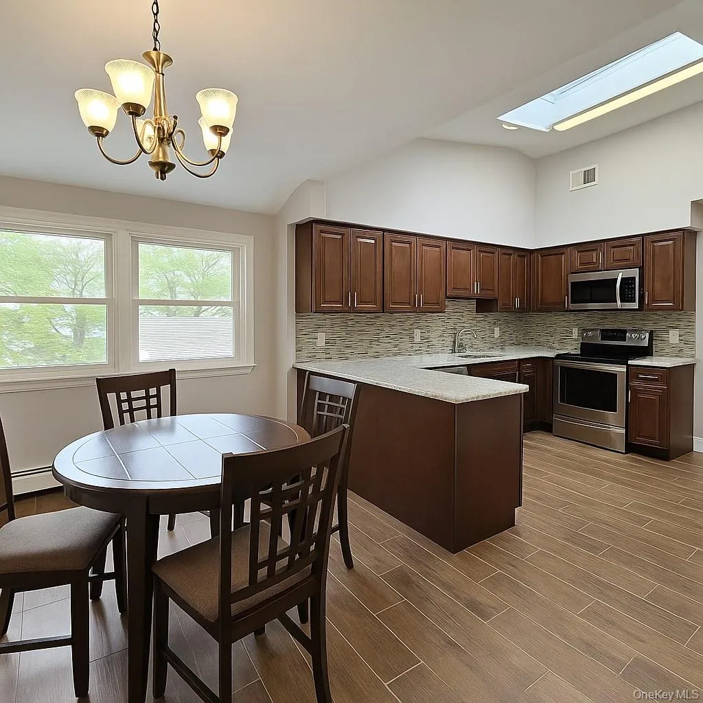 Kitchen featuring appliances with stainless steel finishes, tasteful backsplash, hanging light fixtures, a peninsula, and lofted ceiling Kitchen featuring appliances with stainless steel finishes, tasteful backsplash, hanging light fixtures, a peninsula, and lofted ceiling