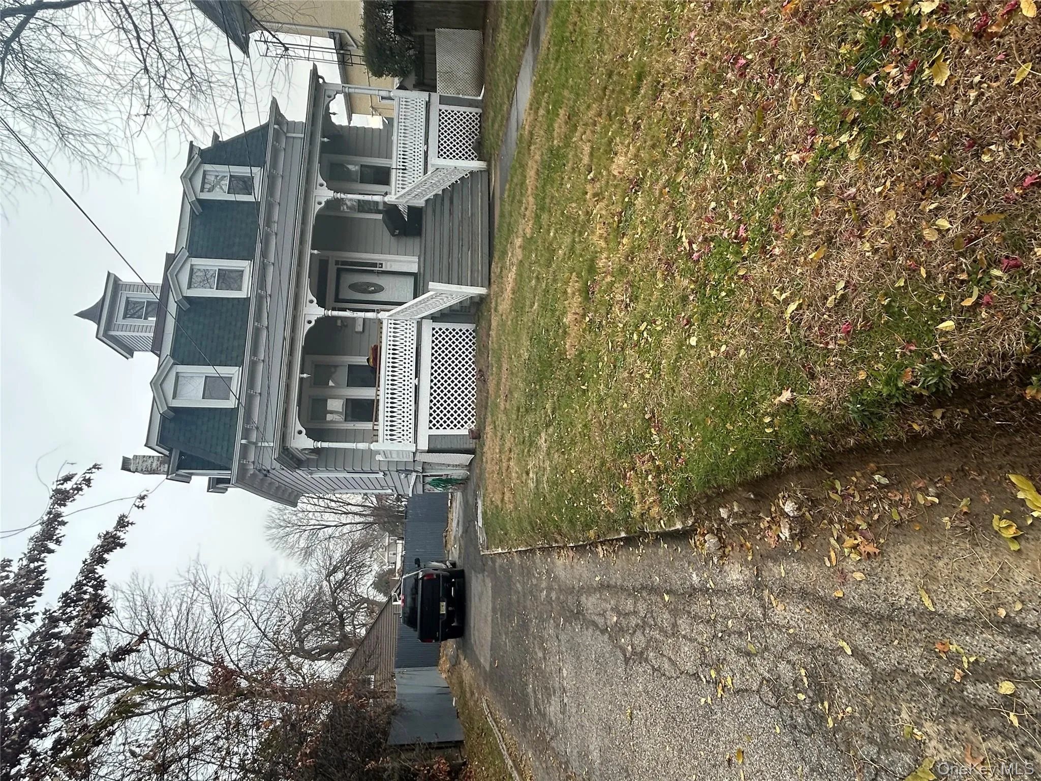 Second empire-style home featuring mansard roof, a porch, driveway, and a chimney Second empire-style home featuring mansard roof, a porch, driveway, and a chimney