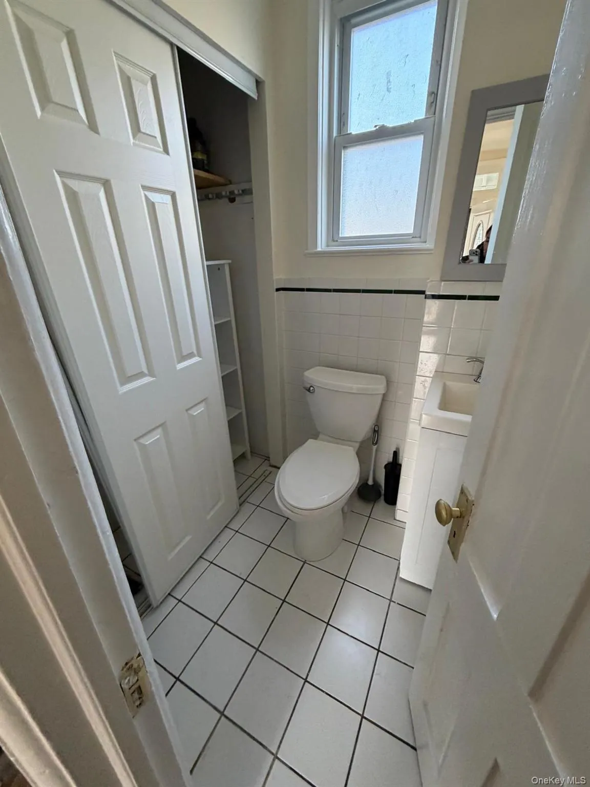 Bathroom with vanity, tile walls, light tile patterned flooring, and wainscoting Bathroom with vanity, tile walls, light tile patterned flooring, and wainscoting