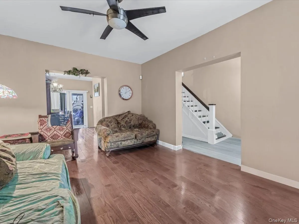 Living room with wood finished floors, stairs, and ceiling fan Living room with wood finished floors, stairs, and ceiling fan