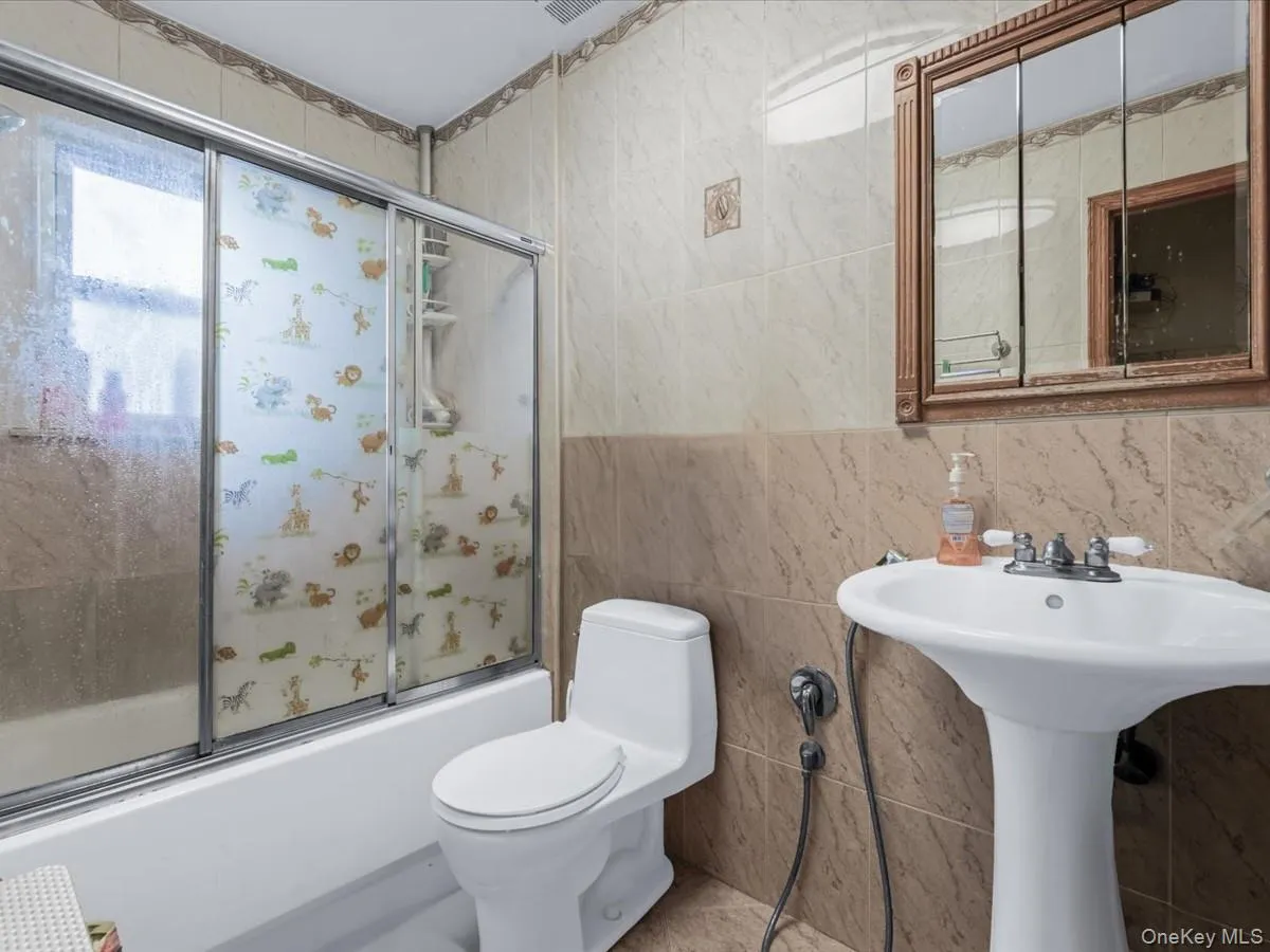 Full bath with bath / shower combo with glass door and tile walls Full bath with bath / shower combo with glass door and tile walls