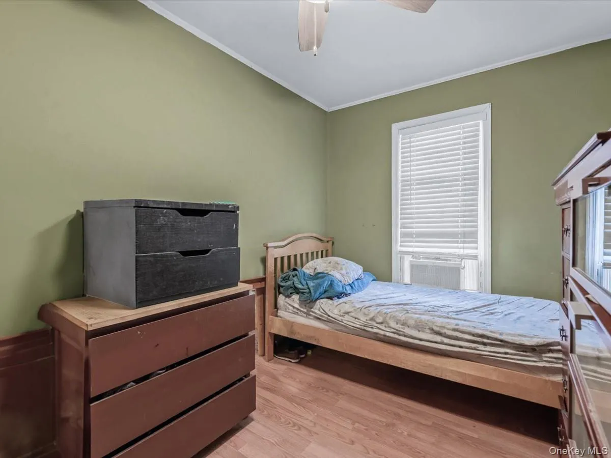 Bedroom featuring light wood-style flooring, ornamental molding, and a ceiling fan Bedroom featuring light wood-style flooring, ornamental molding, and a ceiling fan