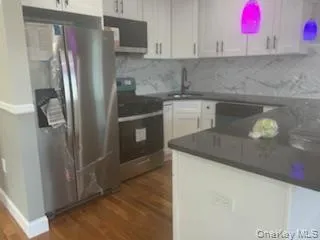 Kitchen featuring stainless steel appliances, white cabinets, dark wood finished floors, and decorative backsplash Kitchen featuring stainless steel appliances, white cabinets, dark wood finished floors, and decorative backsplash
