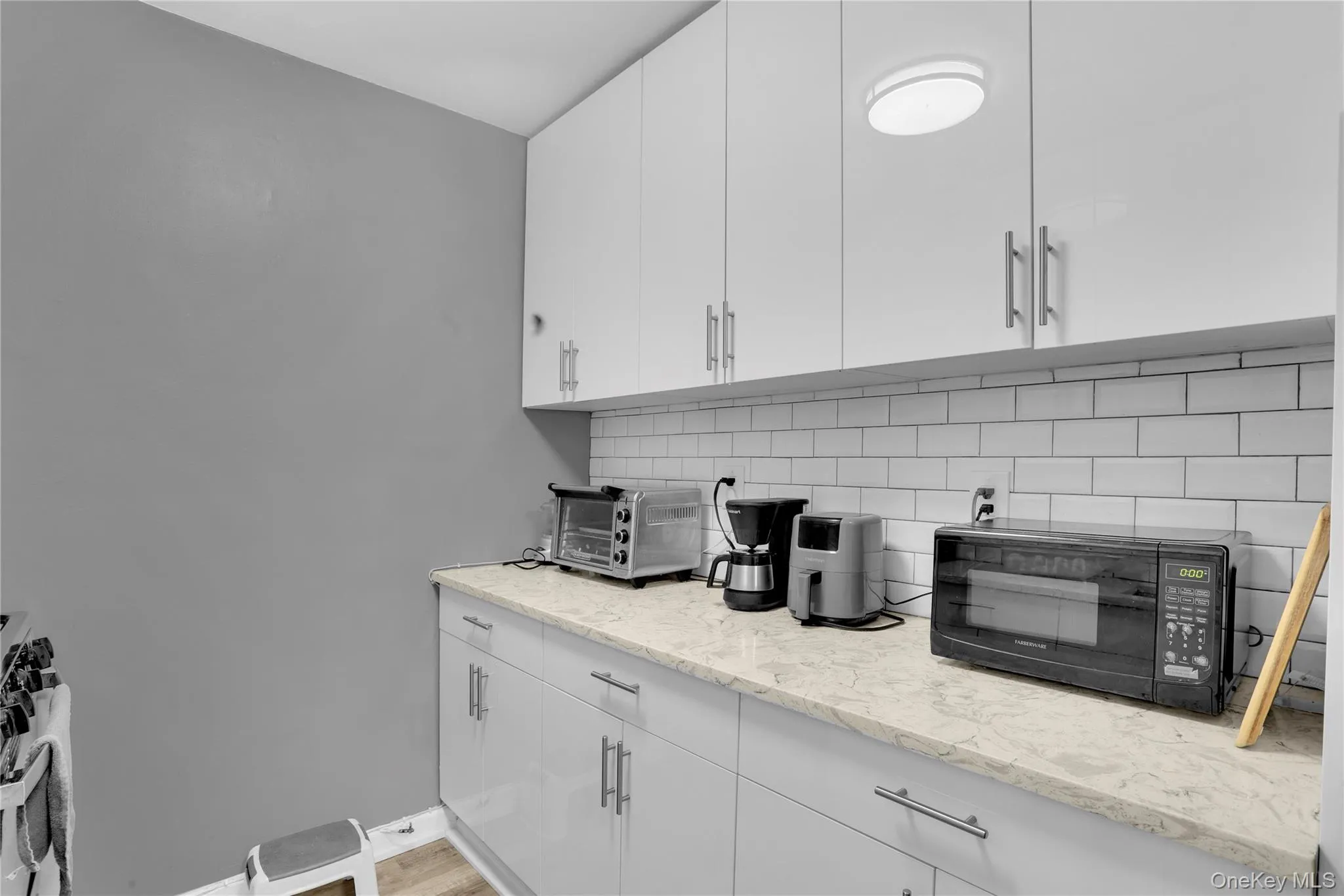 Kitchen featuring black microwave, white cabinetry, decorative backsplash, stainless steel gas range, and modern cabinets Kitchen featuring black microwave, white cabinetry, decorative backsplash, stainless steel gas range, and modern cabinets